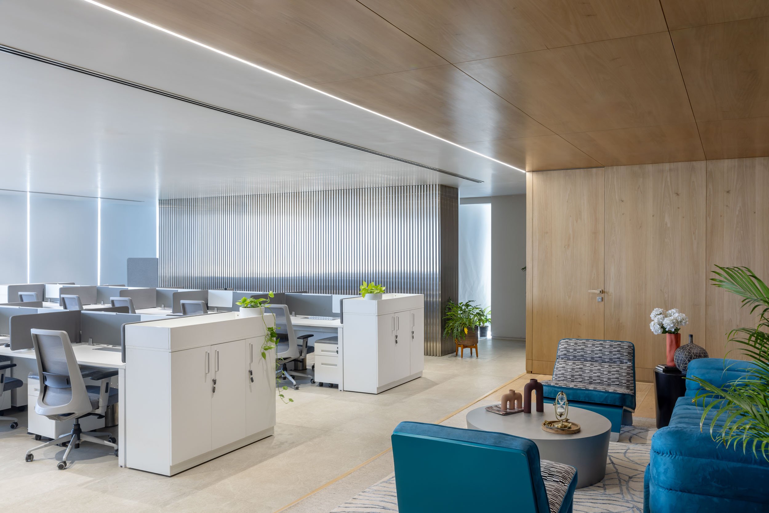 Commercial interior photography showcasing a spacious modern corporate office, highlighting open-plan desk arrangements, custom architectural wood ceilings, and floor-to-ceiling windows
