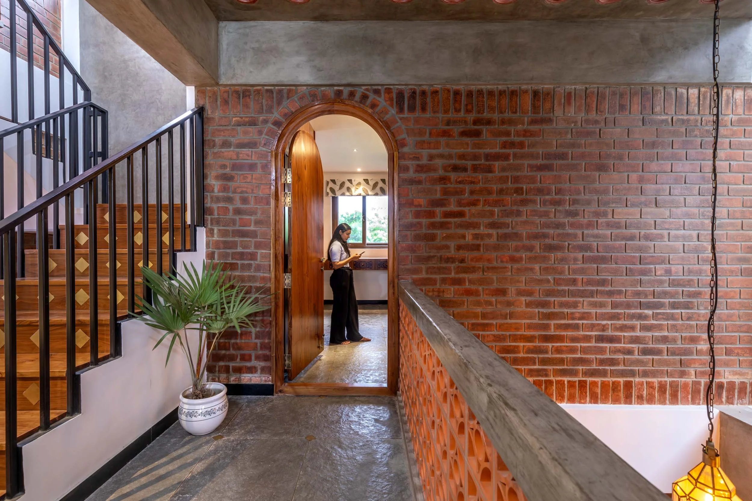 Professional interior architectural photography of a modern residential hallway, highlighting striking exposed brickwork and an arched doorway