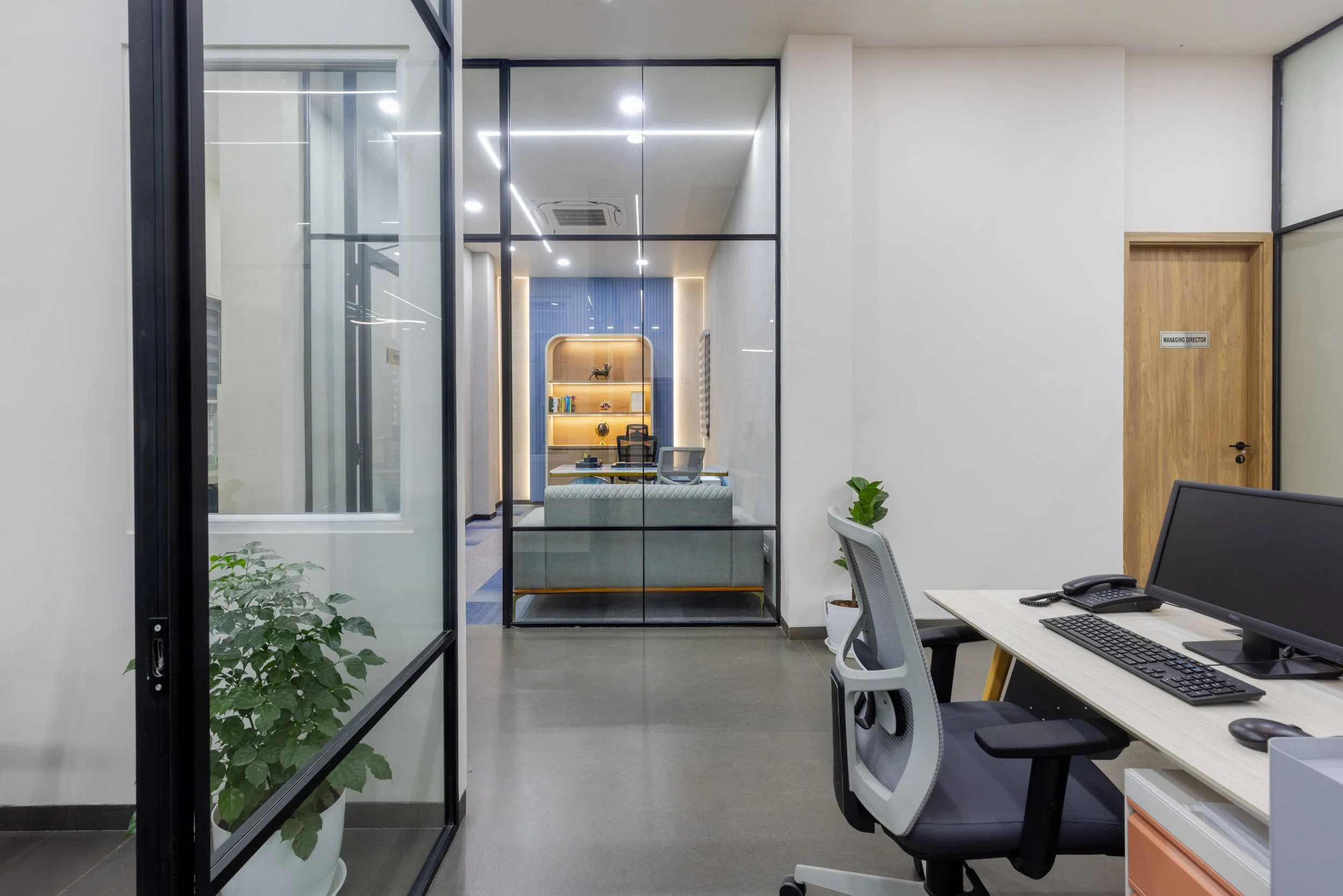 Commercial interior photography showcasing a modern private office design, highlighting transparent glass partitions, ergonomic workspace setups, and clean architectural lines