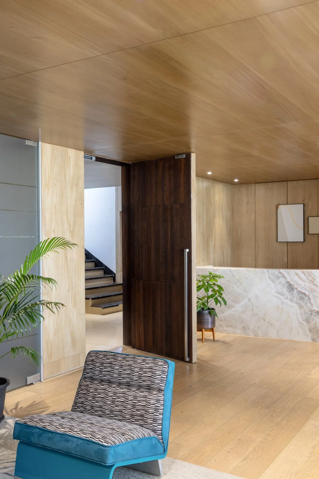 Commercial interior photography showcasing a warm corporate lounge space, highlighting custom architectural wood finishes, modern seating, and integrated indoor greenery