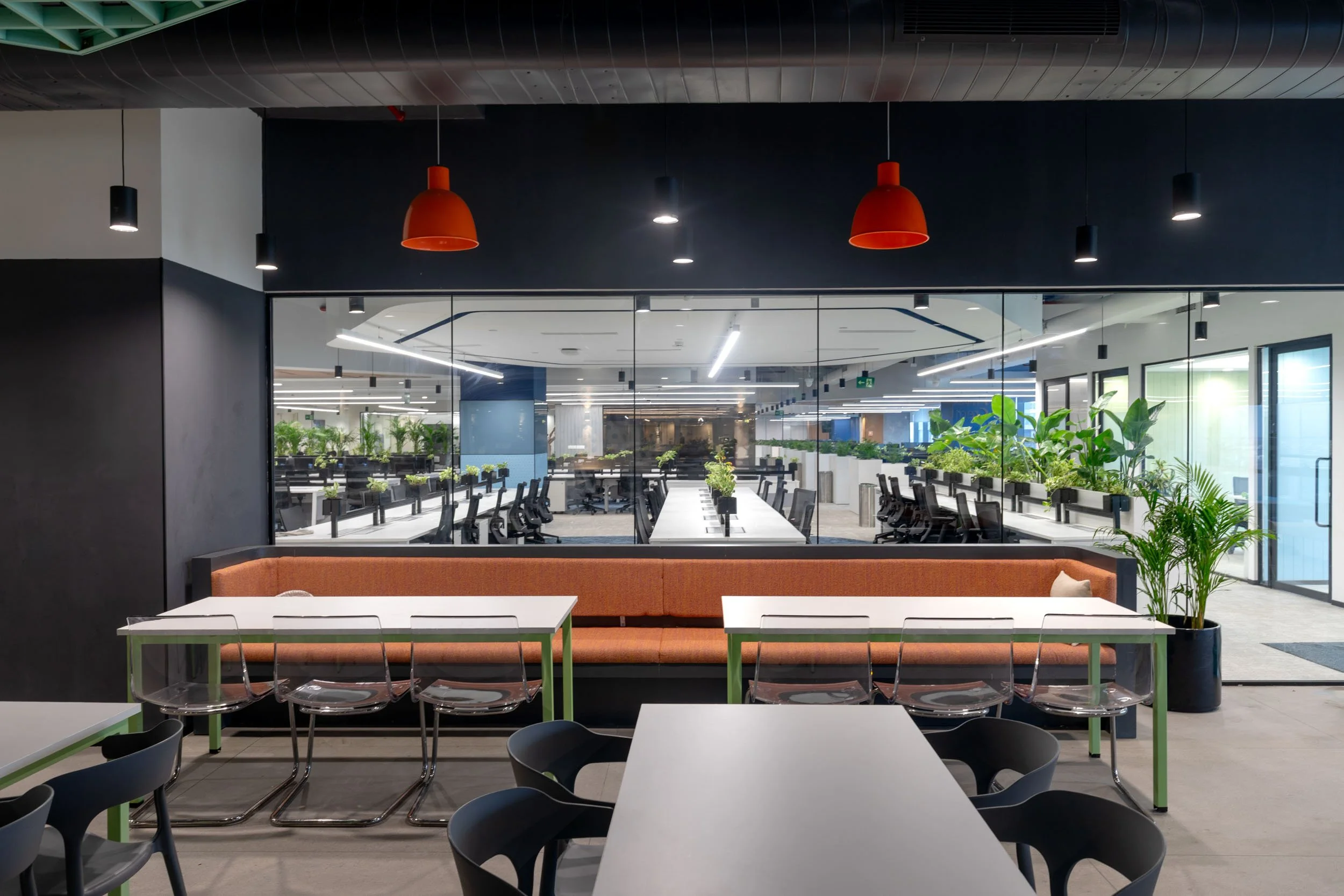 Commercial interior photography showcasing a modern office pantry and collaborative dining area, highlighting biophilic workspace design, vibrant corporate furniture, and custom lighting