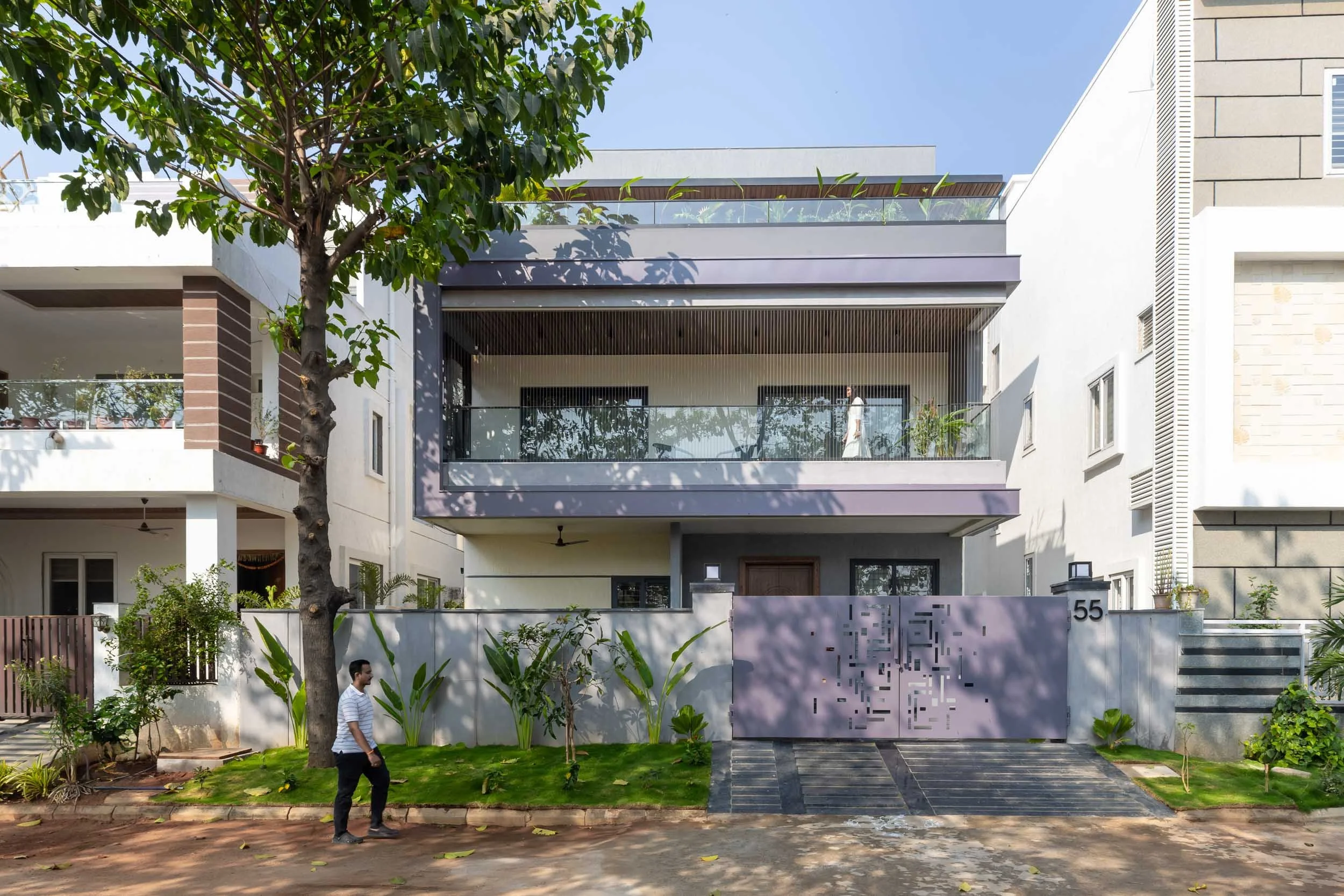 Professional exterior architectural photography of a modern residential home, featuring a clean white facade and distinctive grey slatted balcony shades.