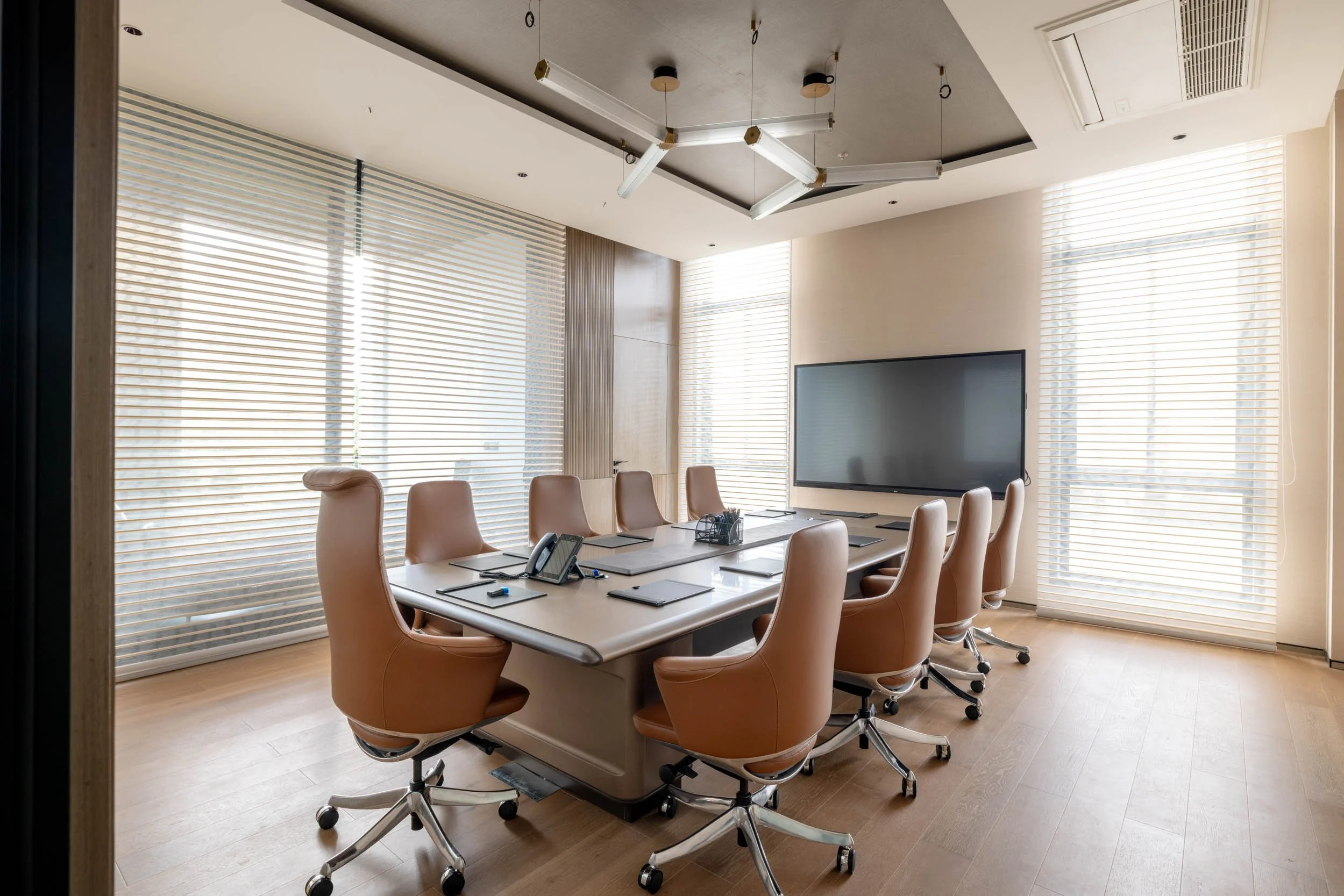 Commercial interior photography showcasing a luxury corporate boardroom, highlighting industrial ceiling design, executive leather seating, and contemporary workspace architecture.