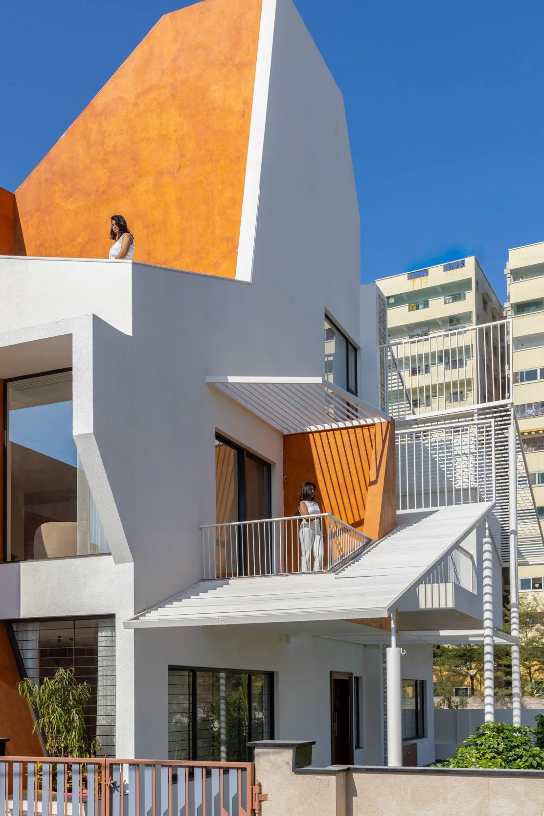 Professional exterior architectural photography of a modern residential home, highlighting striking geometric terracotta accents and a shaded balcony