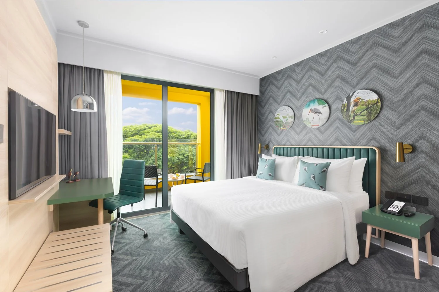 Interior photography of a modern hotel bedroom featuring a large bed with a teal headboard, patterned grey wallpaper, a wall-mounted TV, and large windows with nature views