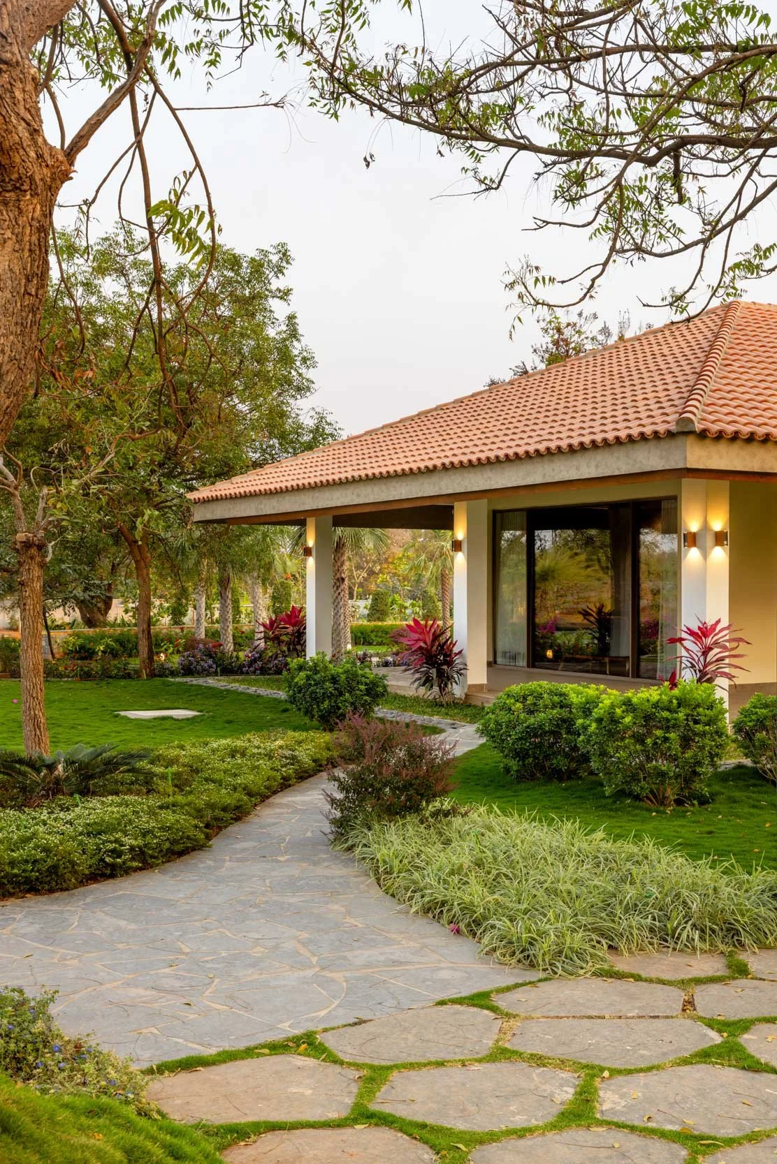 Residential exterior photography featuring a winding stone walkway, lush green garden spaces, and a traditional tiled-roof home.