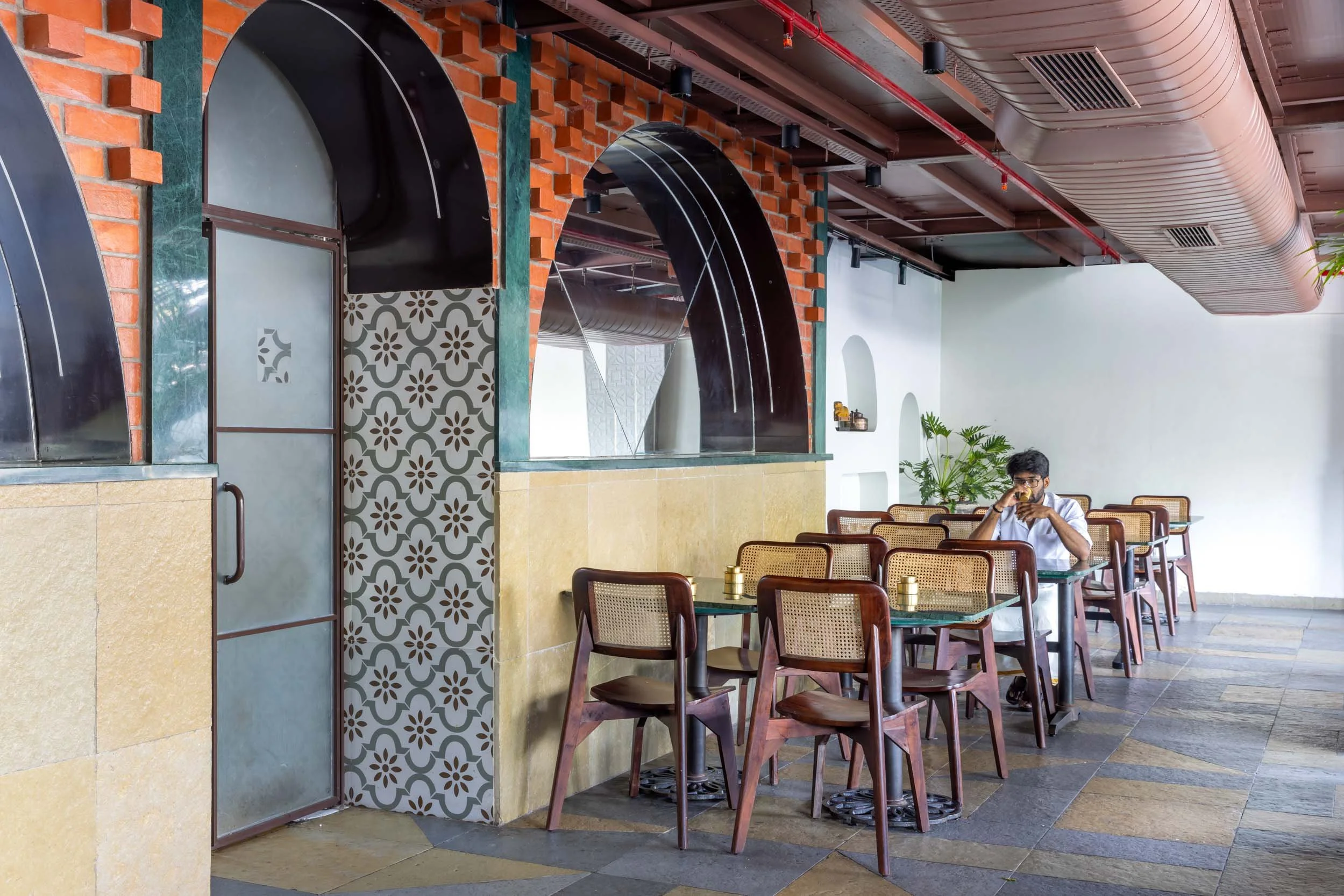 Commercial interior photography showcasing an eclectic restaurant design, highlighting custom arched architecture, vibrant mosaic tile details, and modern hospitality interiors