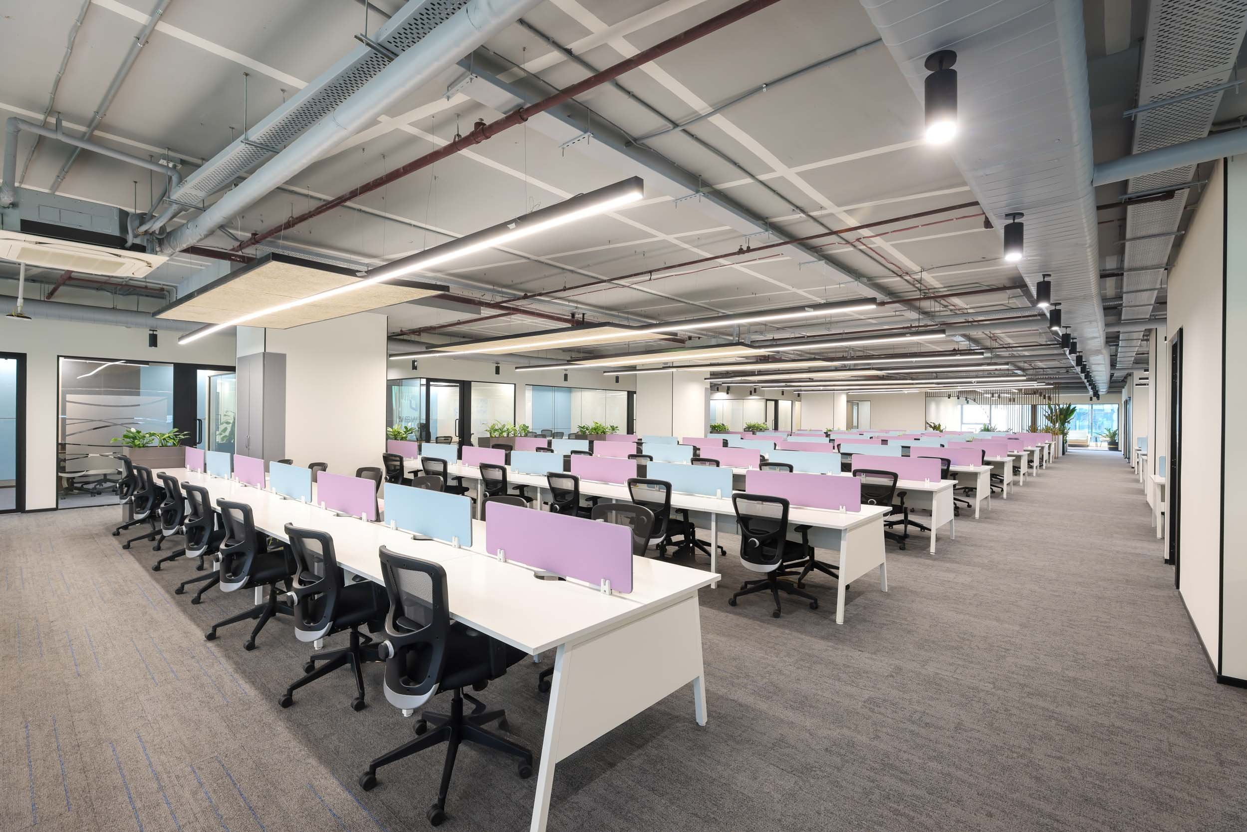 Commercial interior photography showcasing a large open-plan corporate workspace, highlighting modern desk arrangements, ergonomic seating, and industrial ceiling design