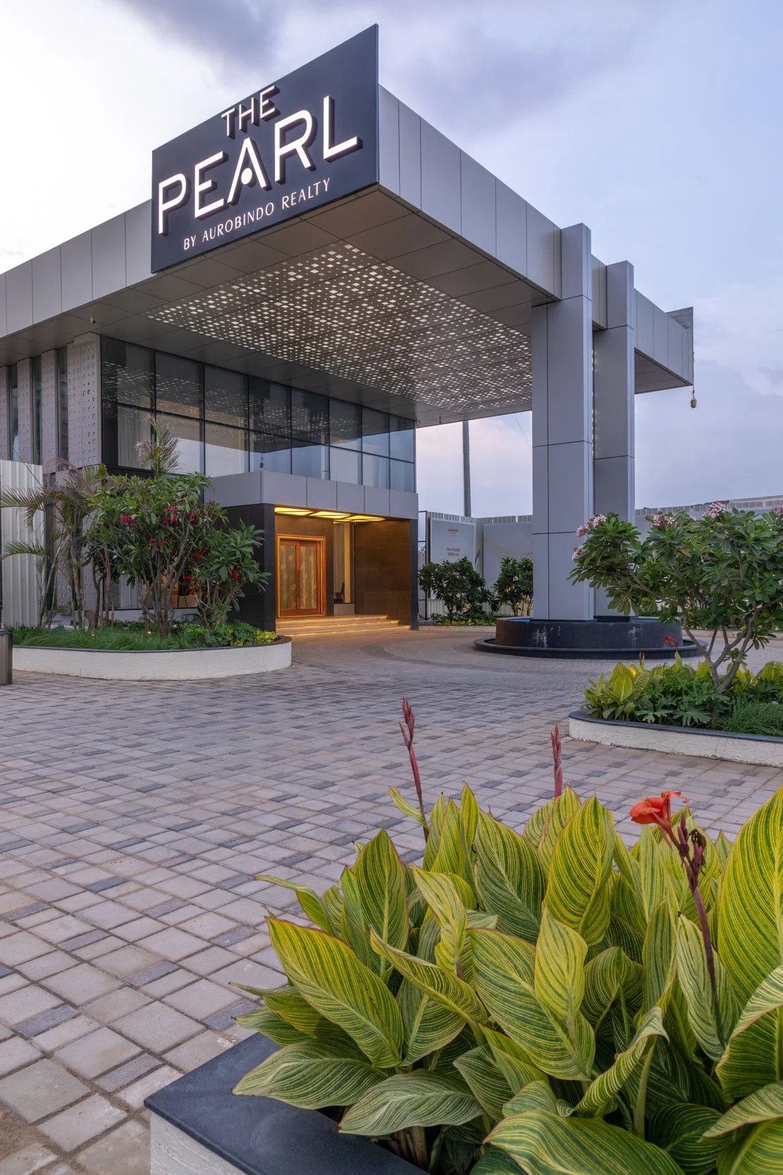 Exterior commercial architecture photography showcasing a modern corporate building entrance, highlighting a large portico structure and integrated ground-level landscaping