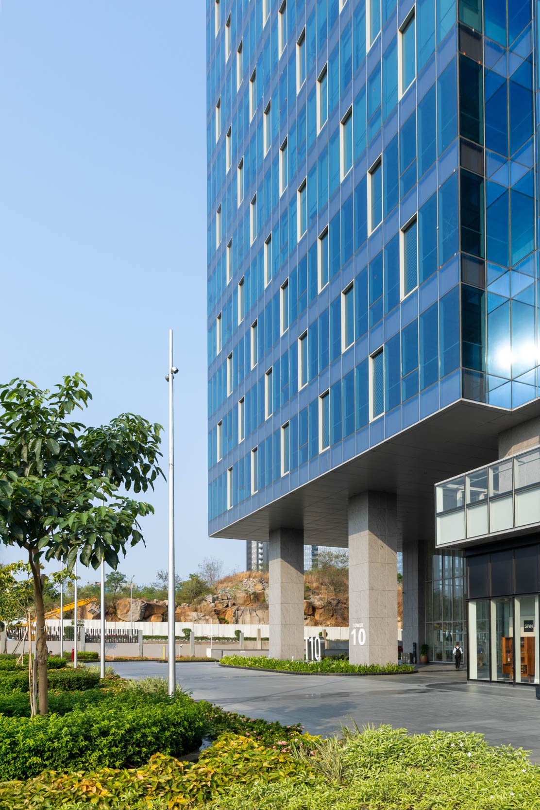 Professional commercial architecture photography capturing a low-angle perspective of a modern office building, highlighting a striking blue glass facade and a cantilevered design