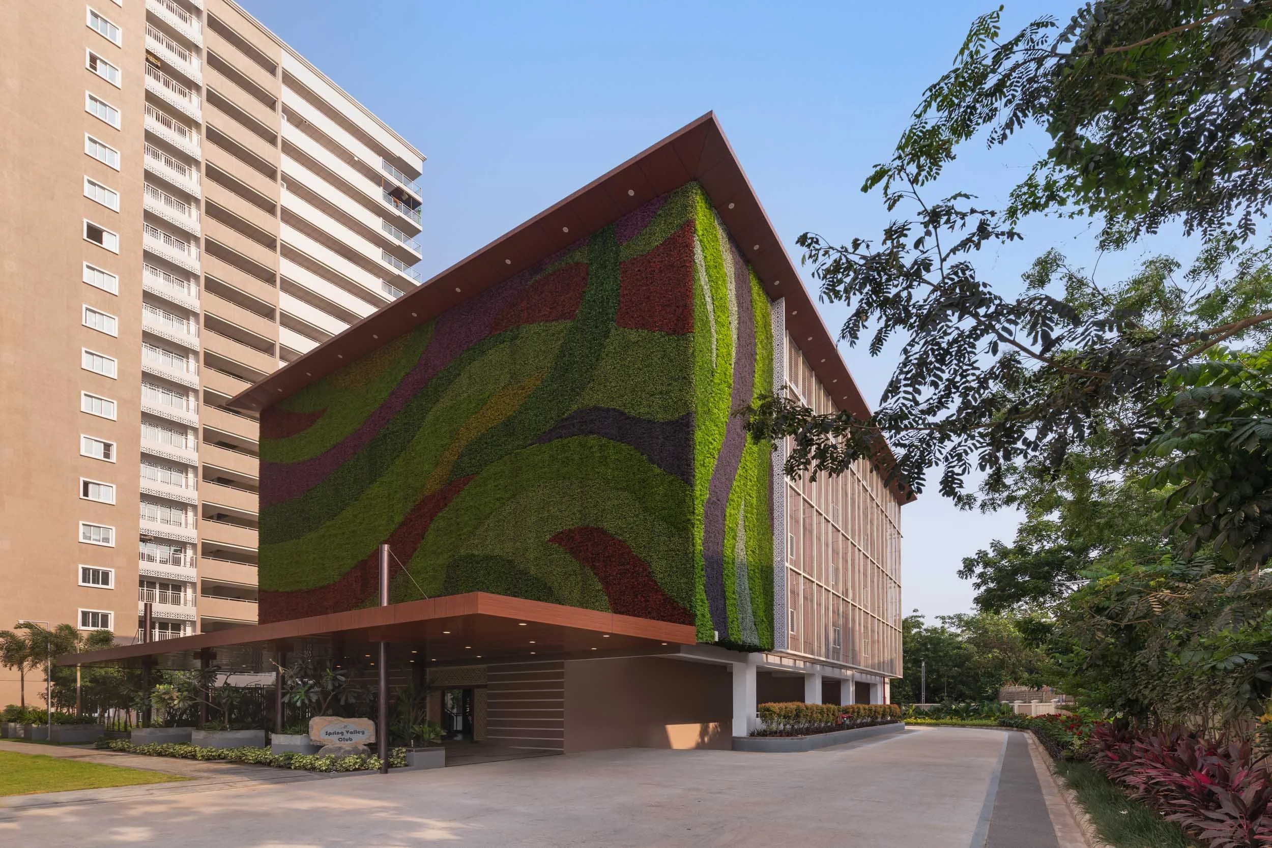 Real estate exterior photography of a modern architectural design, highlighting a distinctive patterned facade, a welcoming driveway approach, and integrated landscaping