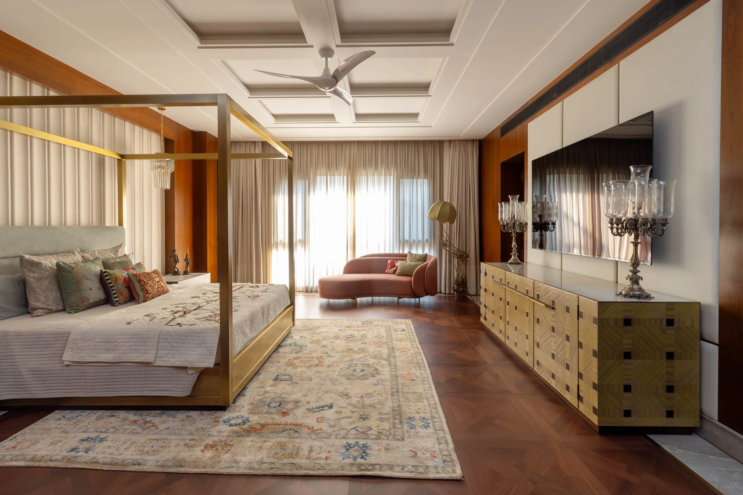 Professional interior photography of a spacious, modern residential bedroom featuring a wooden four-poster bed and warm natural light.