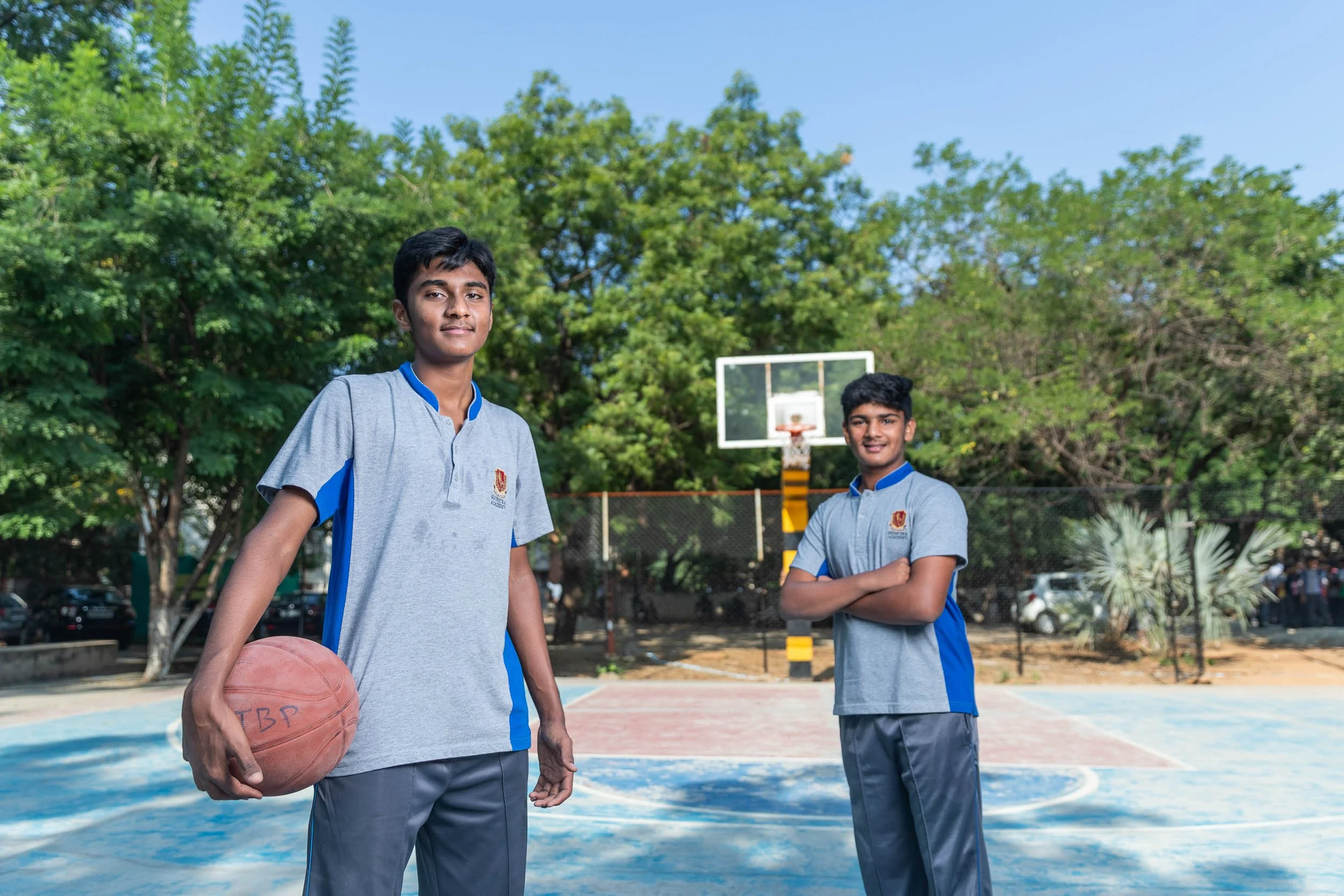 Exterior campus photography highlighting sports facilities with students on an outdoor basketball court | Ravi Varma Photography & Film