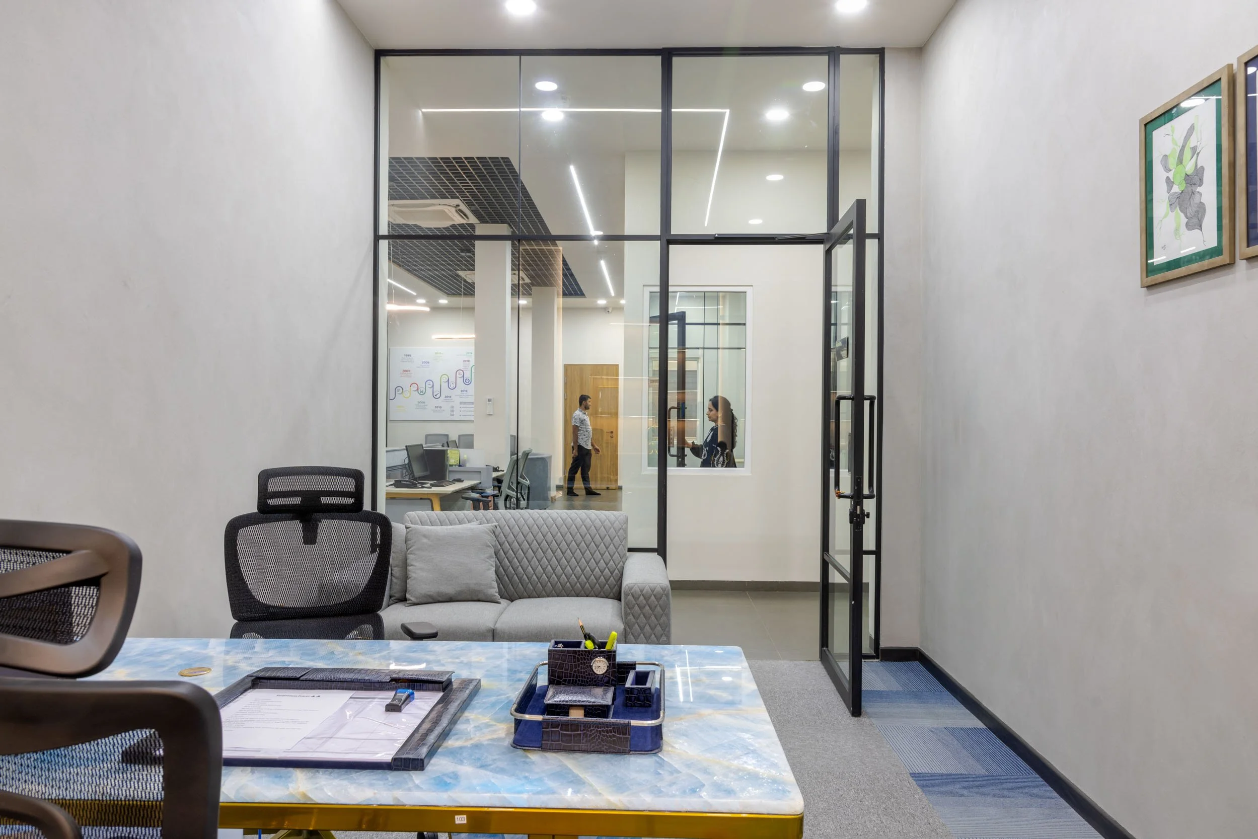 Commercial interior photography showcasing a modern private office design, highlighting transparent glass walls, contemporary workspace setups, and integrated lounge seating