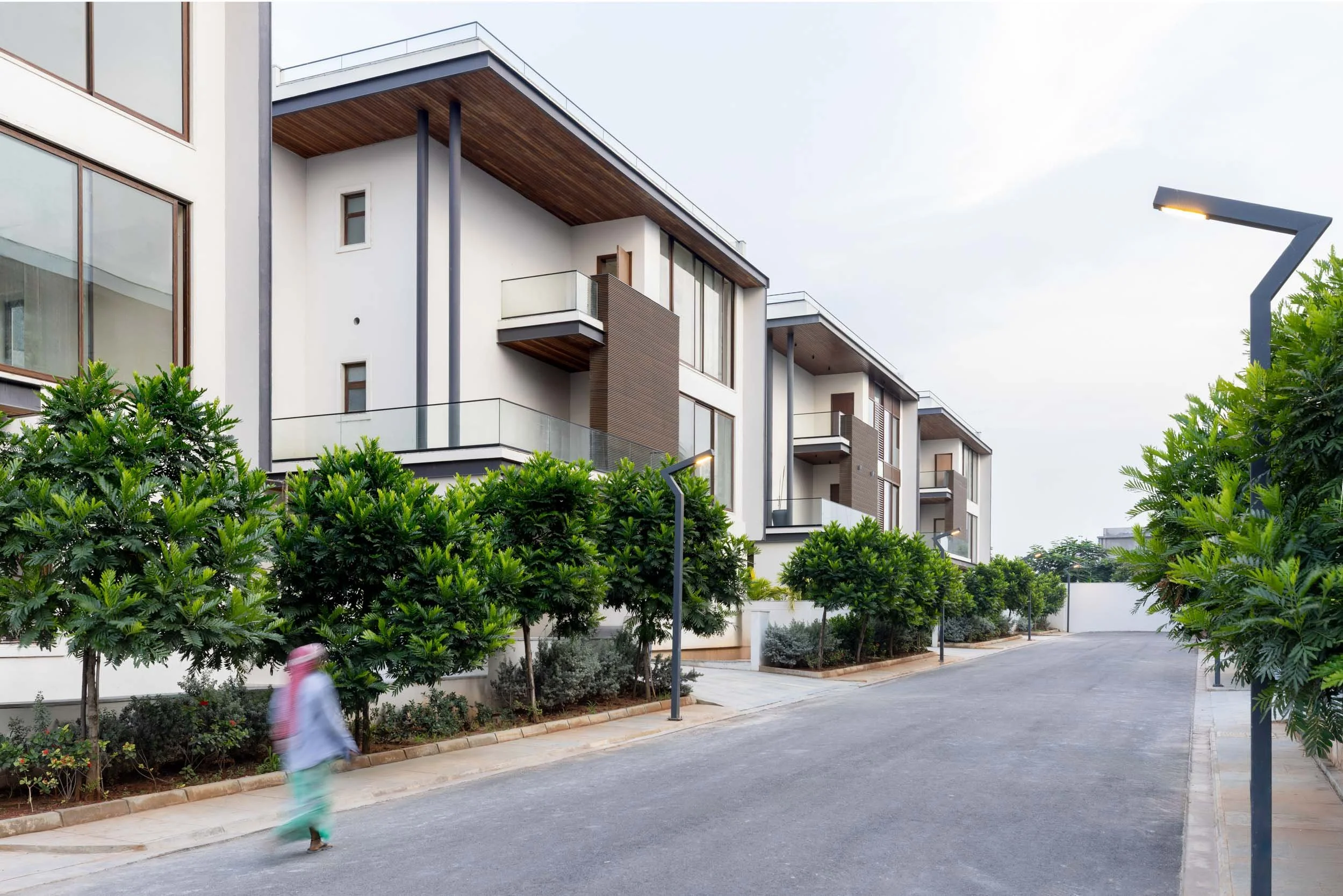 Residential real estate exterior photography capturing a modern streetscape with contemporary townhomes, paved roads, and landscaped pedestrian walkways