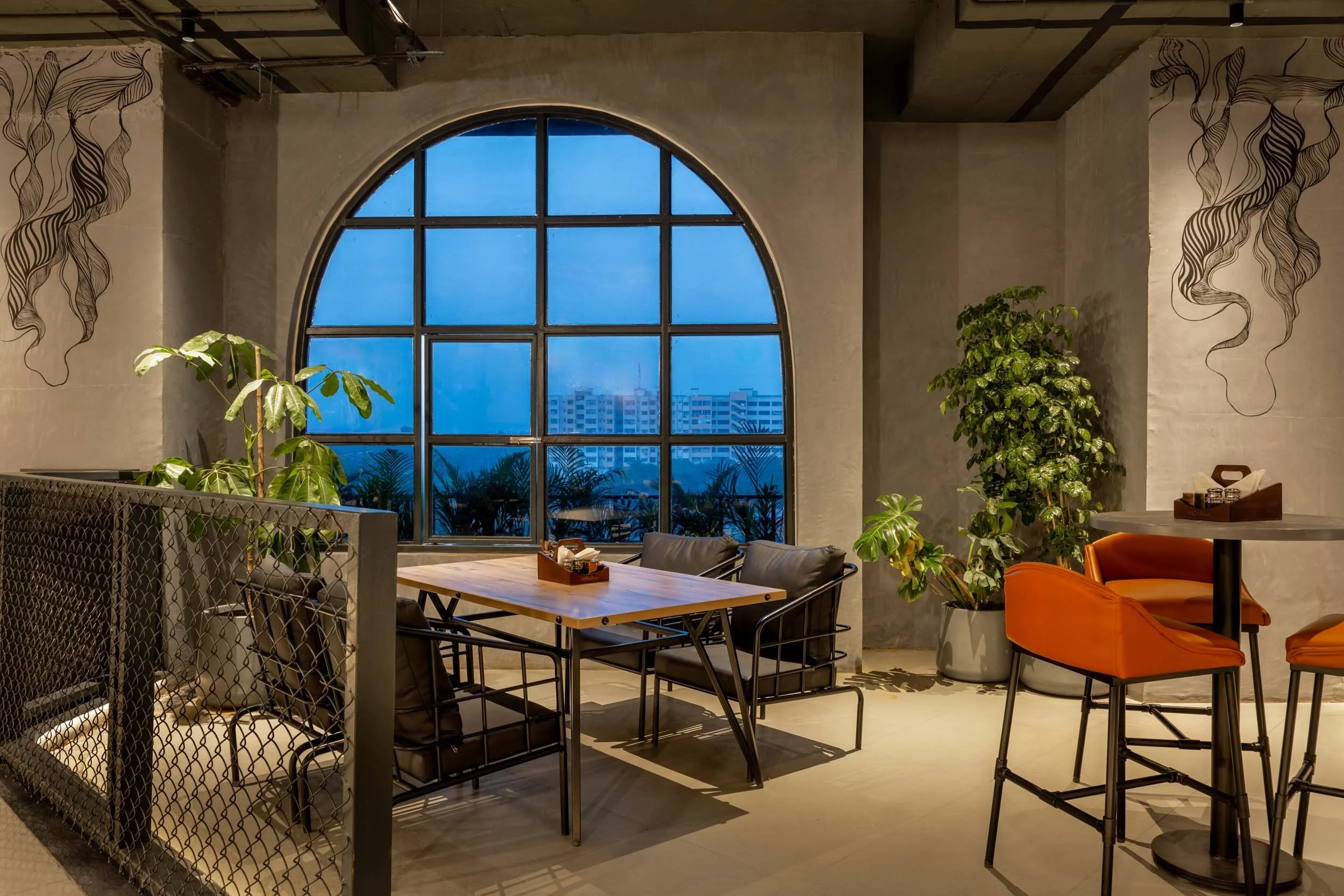 Commercial interior photography showcasing an industrial-modern restaurant, highlighting architectural arched windows, twilight ambient lighting, and inviting hospitality interior design