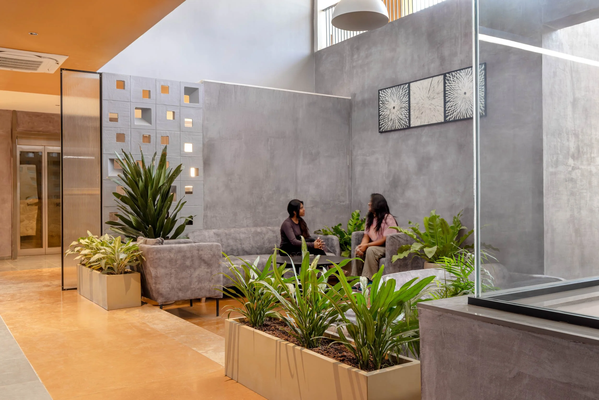 Professional interior architecture photography of a modern commercial office space, highlighting an open-plan lounge, integrated indoor planters, and abundant natural light.