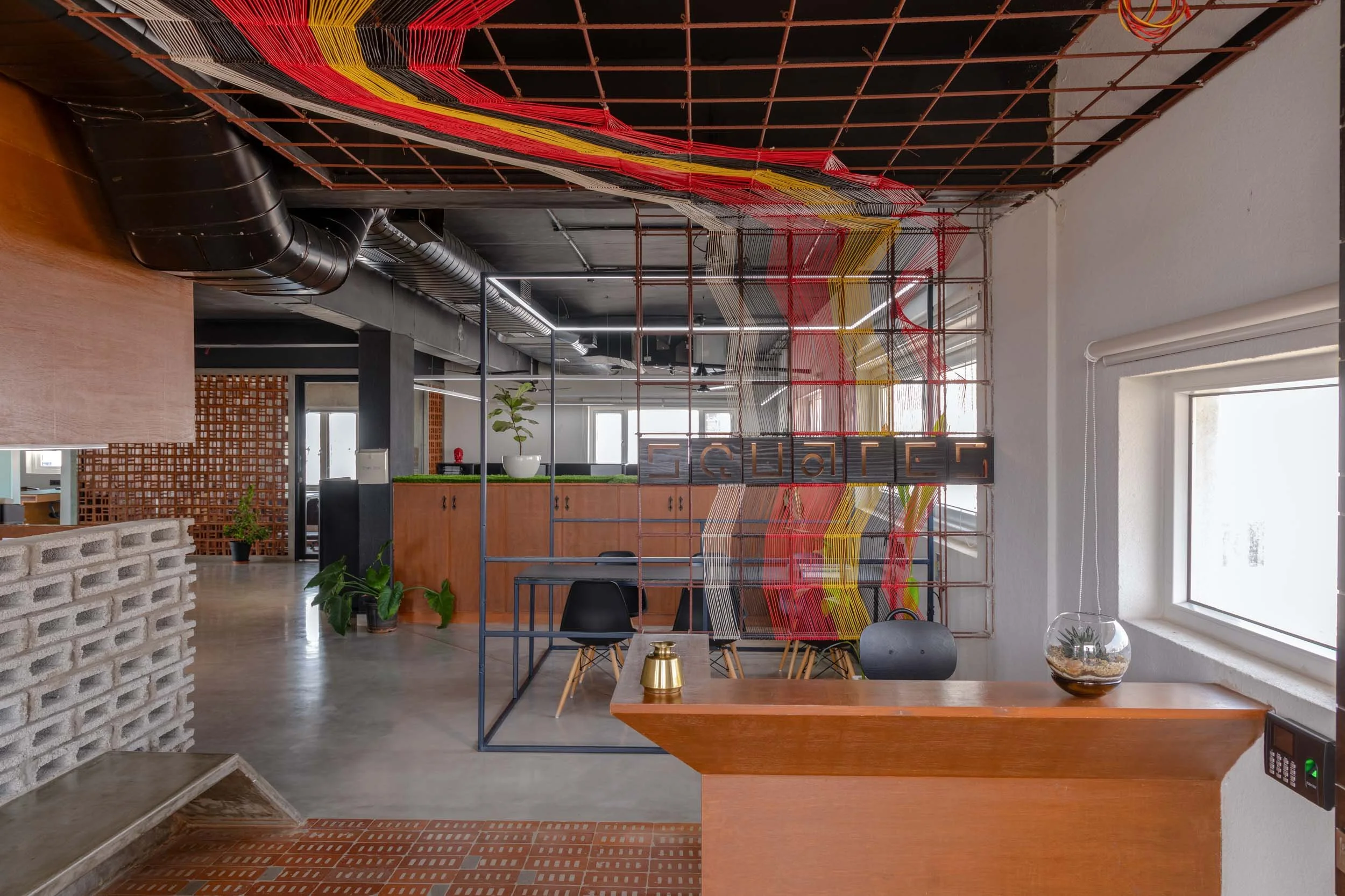 Commercial interior photography showcasing a creative industrial workspace design, highlighting colorful exposed ceiling elements, brick pillars, and modern office architecture