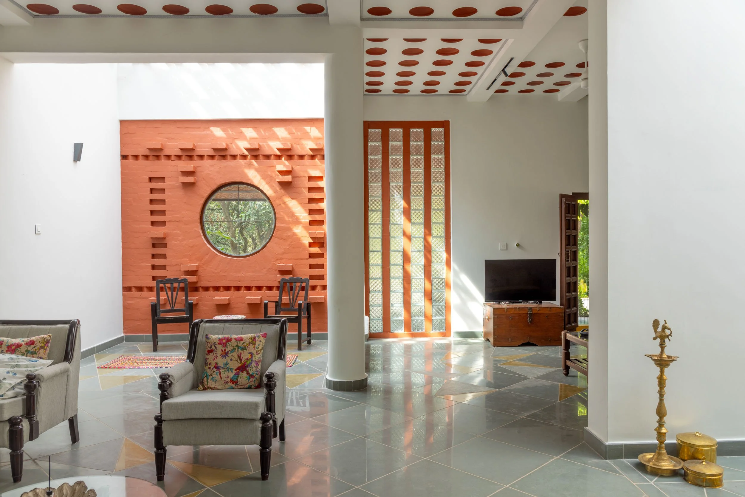 Professional interior architectural photography of a unique residential living space, highlighting traditional design elements, a striking terracotta wall, and classic brass decor.