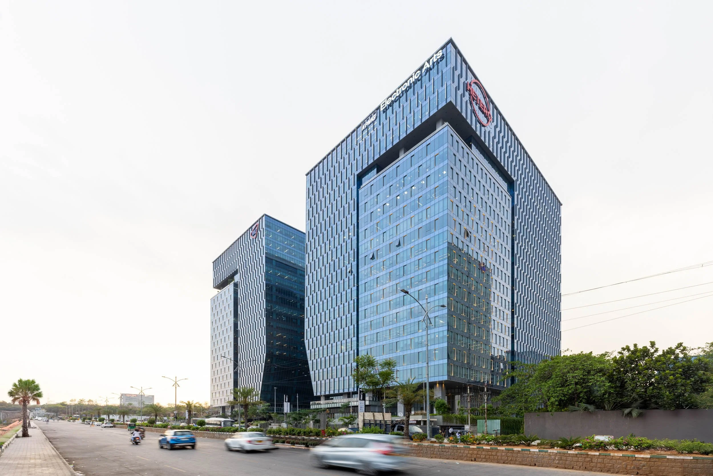 Professional commercial architecture photography showcasing a striking modern office building with an angular glass facade and a bustling street-level view.
