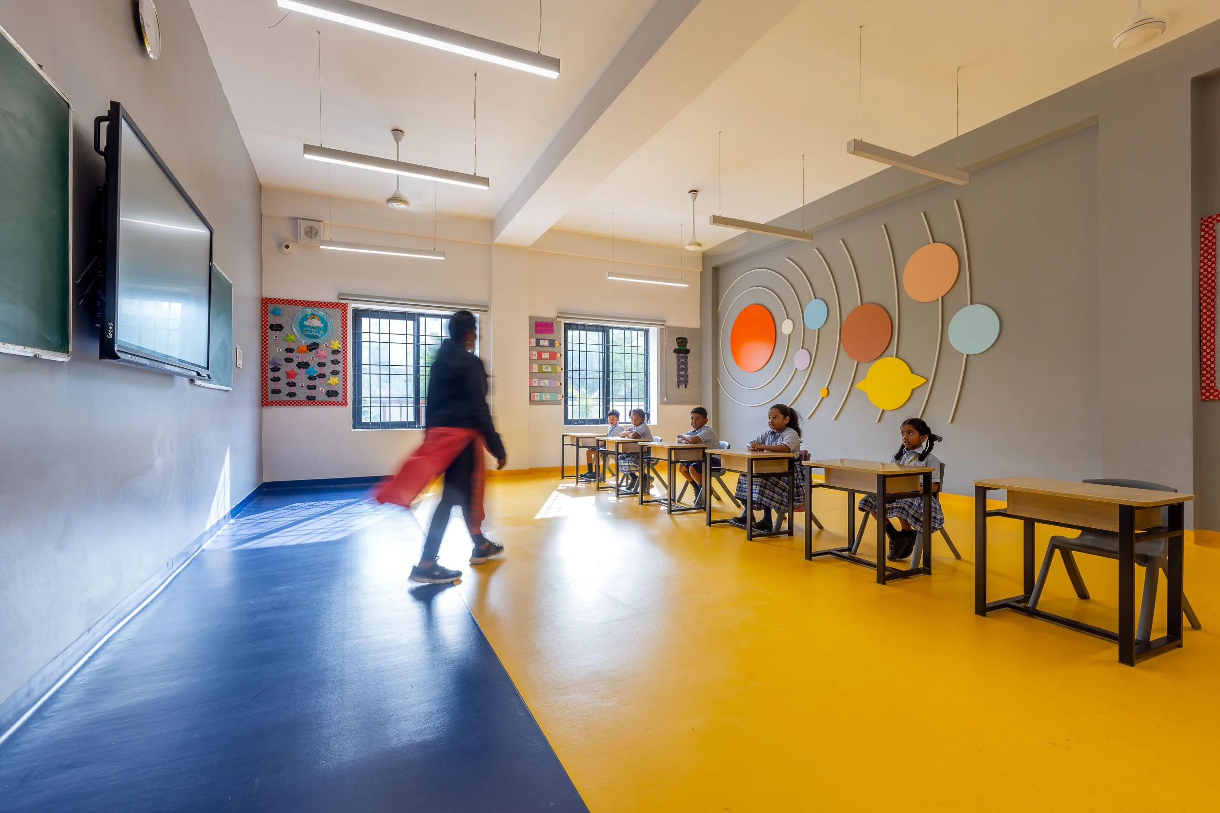 nterior school photography of a brightly colored, modern school corridor with a student walking to class