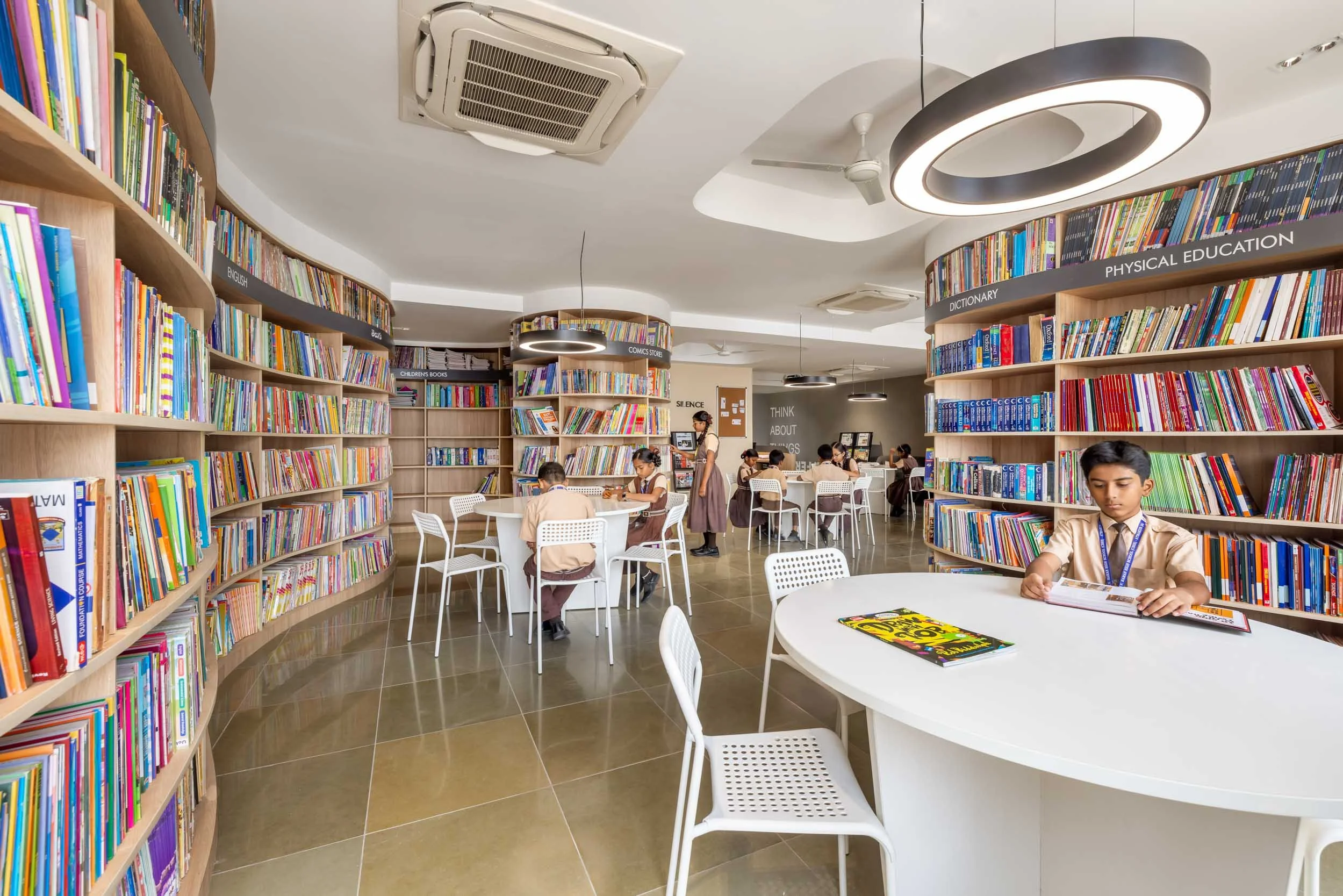 Professional interior architecture photography of a vibrant modern bookstore or library space, highlighting sweeping curved tables, extensive bookshelves, and bright, contemporary lighting.