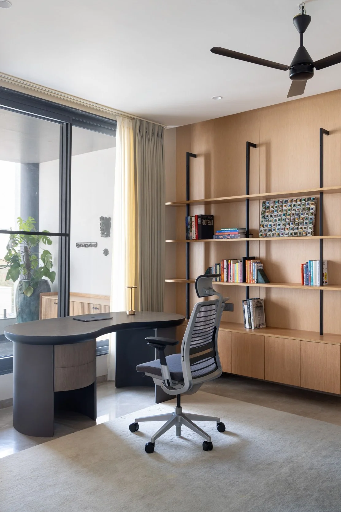 Professional interior photography of a bright, modern residential home office featuring custom wooden shelving and natural light