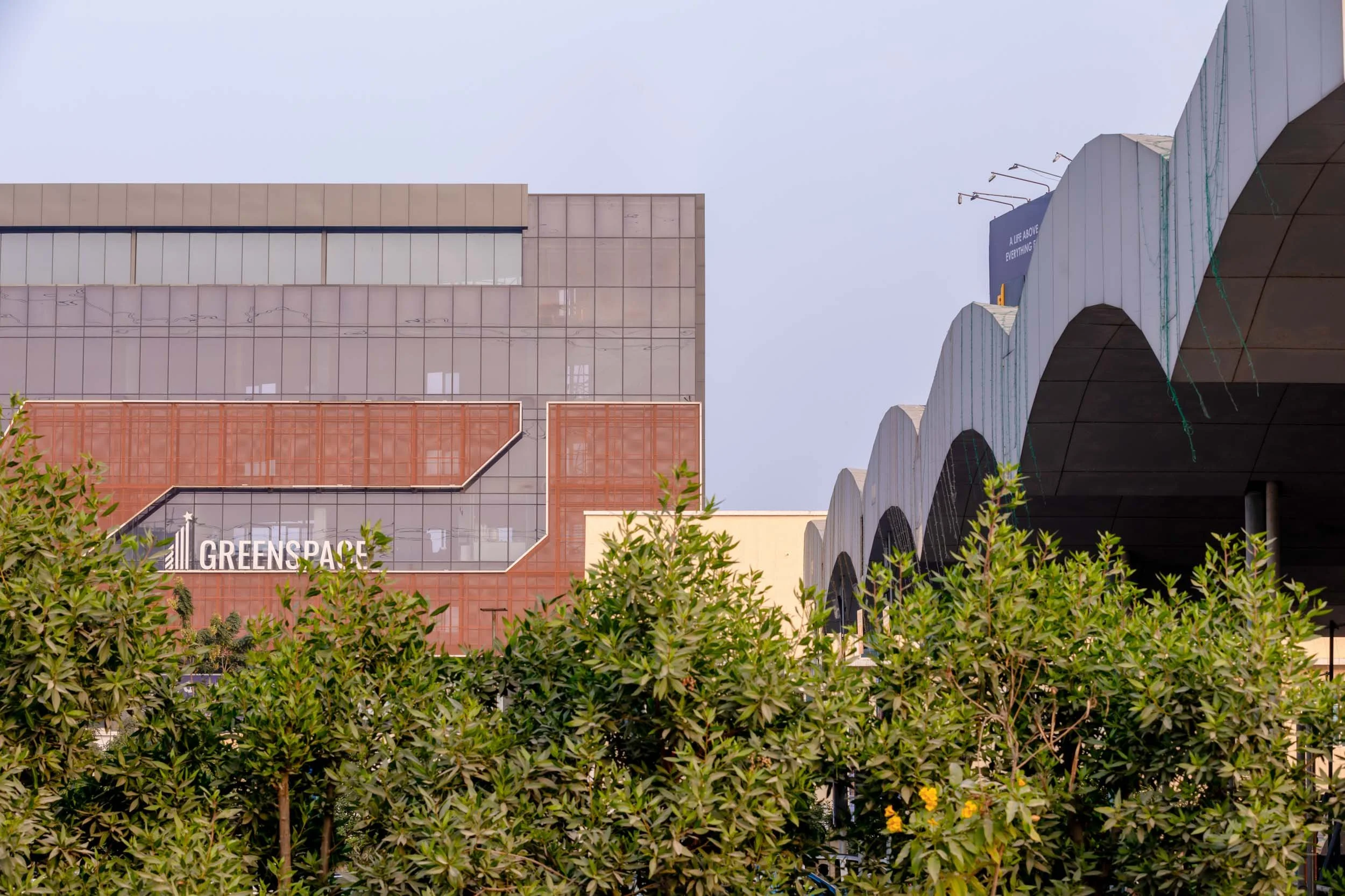 Commercial architecture photography capturing a modern business or cultural complex featuring unique wavy roof structures, textured facades, and integrated urban greenery