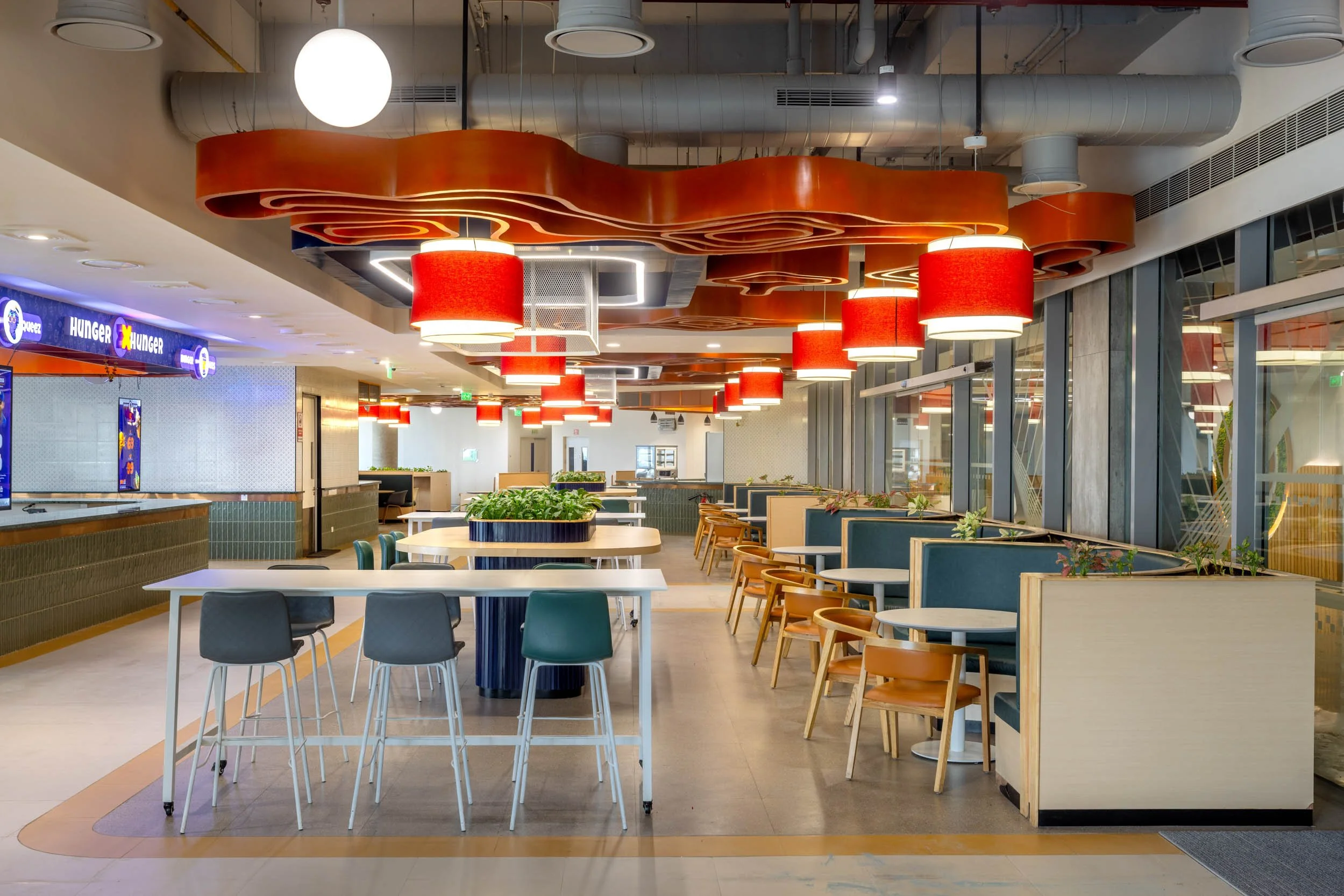 ommercial interior photography showcasing a colorful industrial-modern cafeteria, highlighting exposed ceiling architecture, vibrant lighting fixtures, and playful hospitality interior design