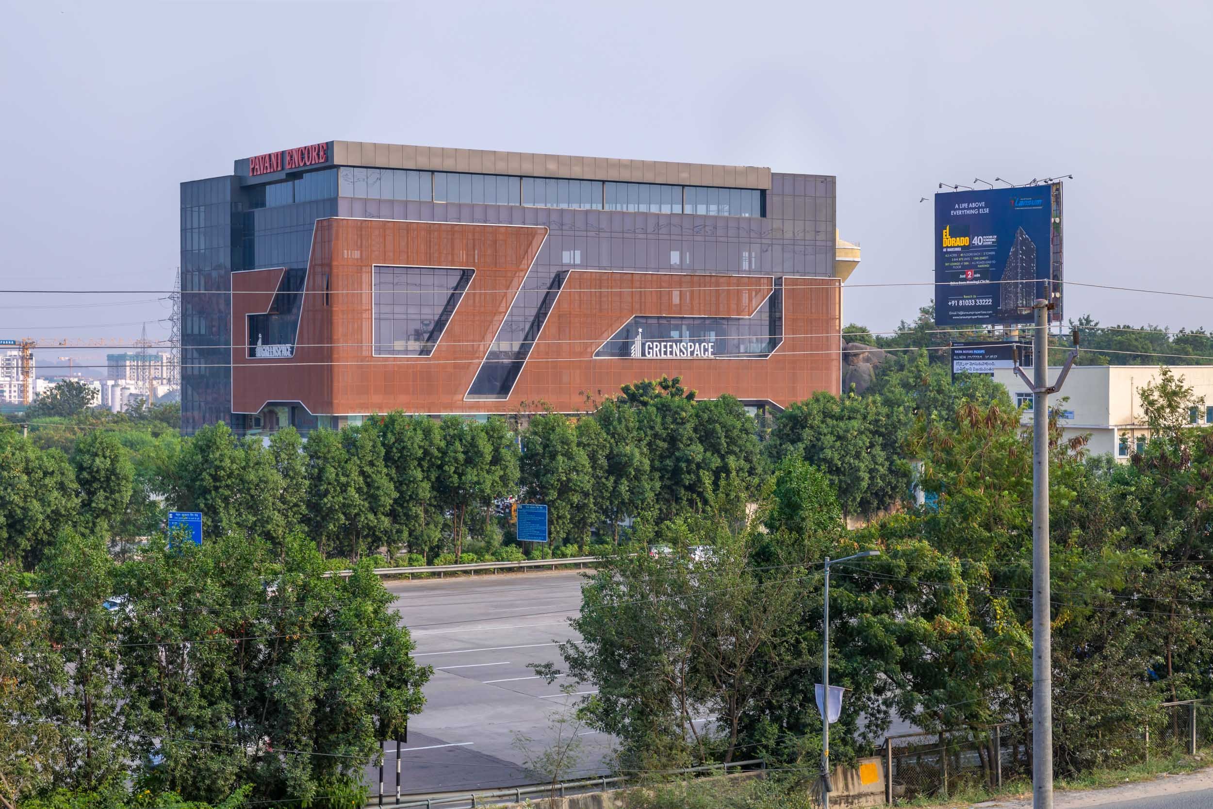 Exterior commercial architecture photography showcasing a modern office building with unique brickwork, vibrant orange architectural details, and integrated landscaping