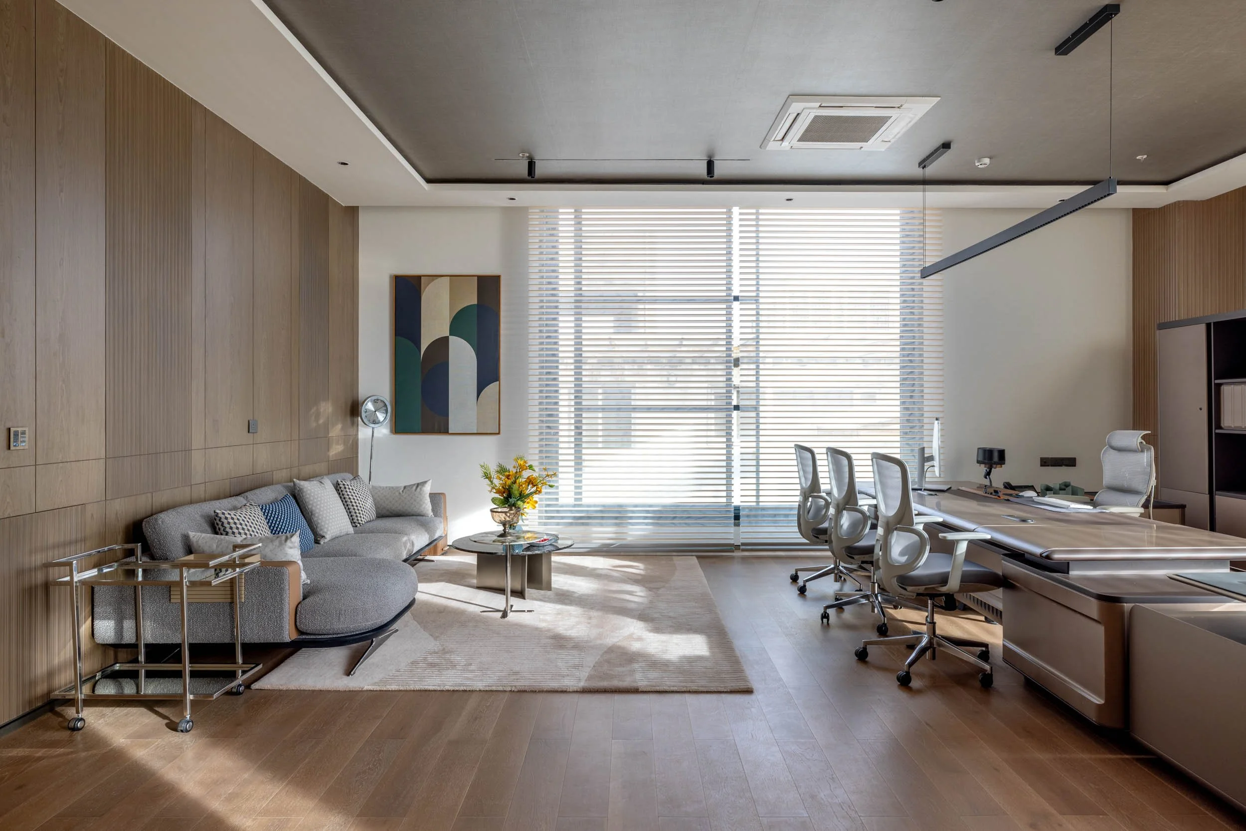 Commercial interior photography showcasing a luxury private office design, highlighting custom wood paneling, natural light, lounge seating, and a modern workspace layout