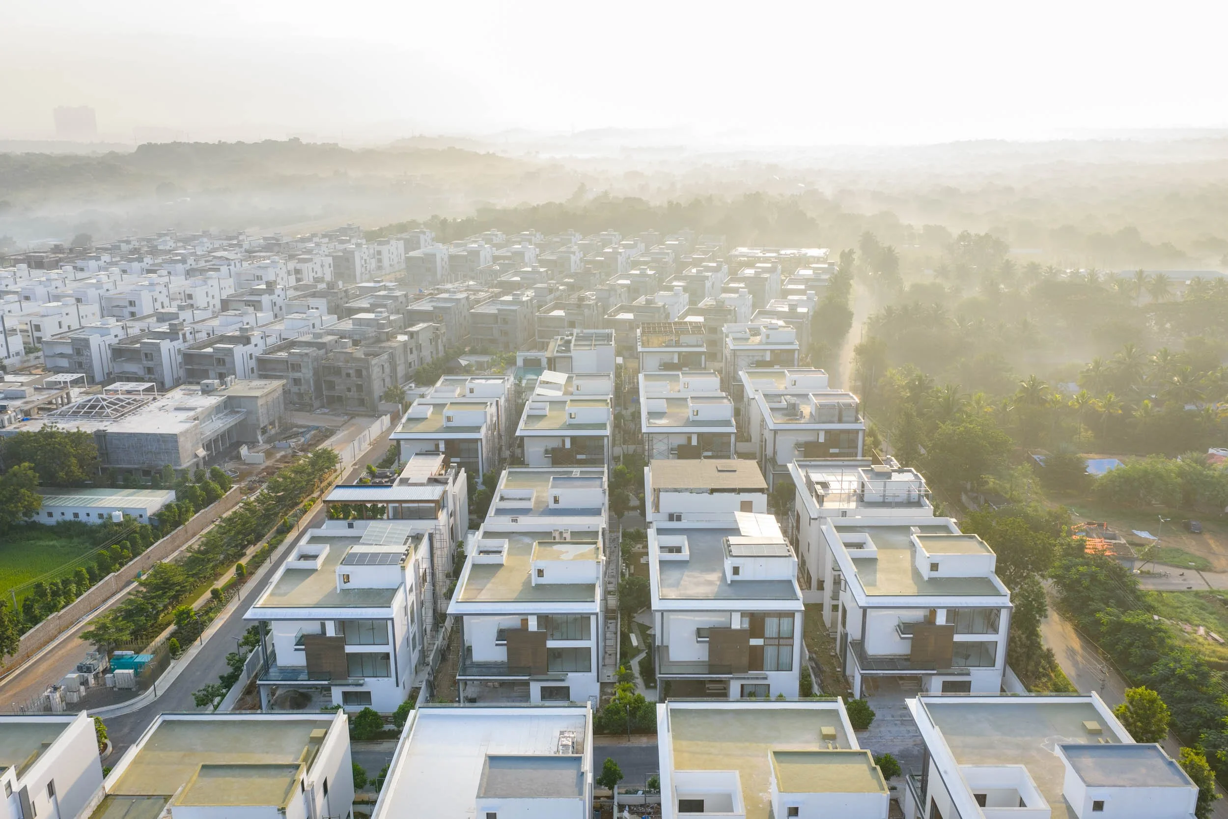 erial real estate photography showcasing a modern master-planned neighborhood, highlighting luxury villas, structured urban design, and beautiful golden hour lighting