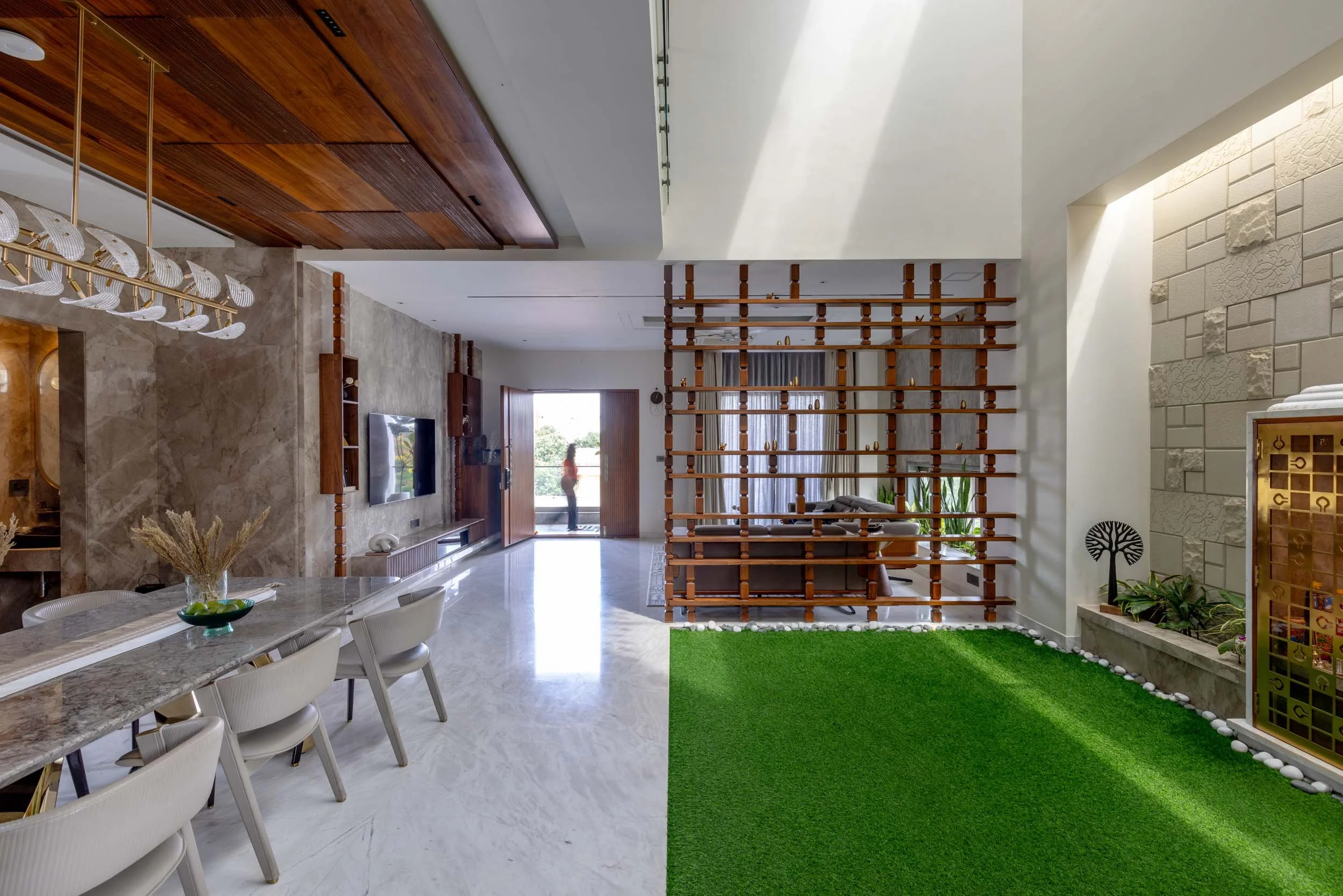 Professional architectural photography of a modern residential home, highlighting a seamless indoor-outdoor living space, an open dining area, and unique integrated green spaces.