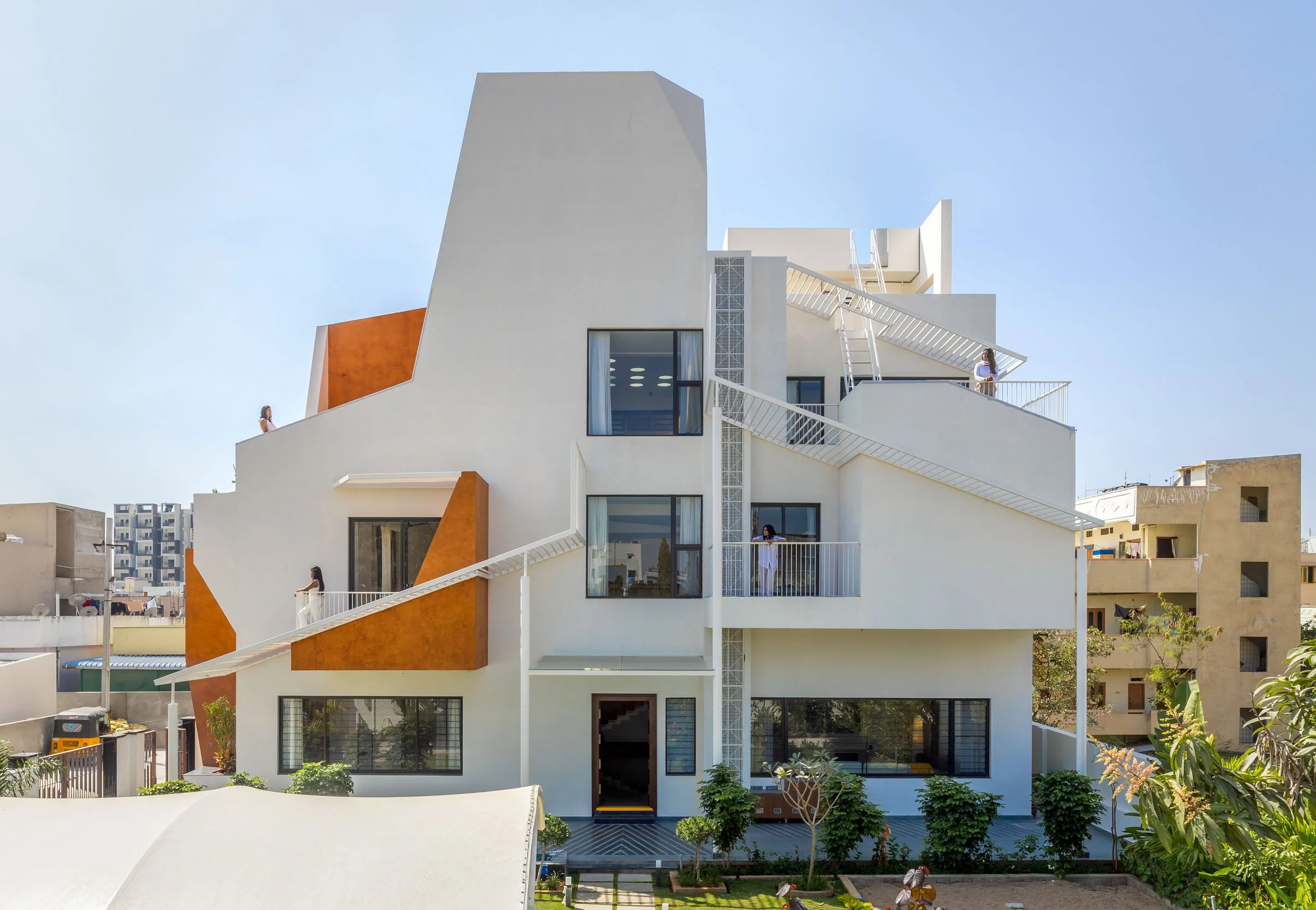 Professional exterior architectural photography of a multi-story modern residential home highlighting bold terracotta accents and large glass windows