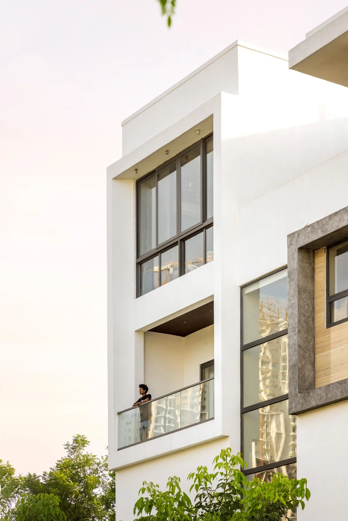 Professional exterior architectural photography of a modern multi-story residential home, highlighting a clean white geometric facade, large glass windows, and distinctive architectural volumes