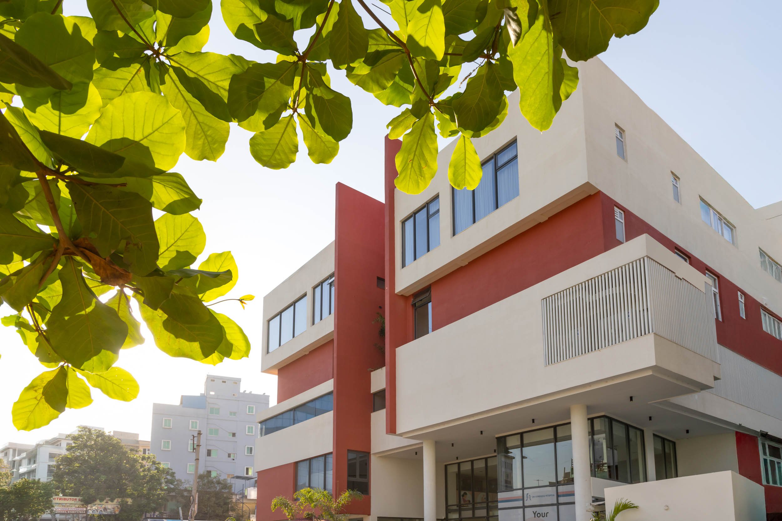 Commercial architecture photography showcasing a modern office building exterior with a cantilevered design, geometric facade details, and natural tree framing