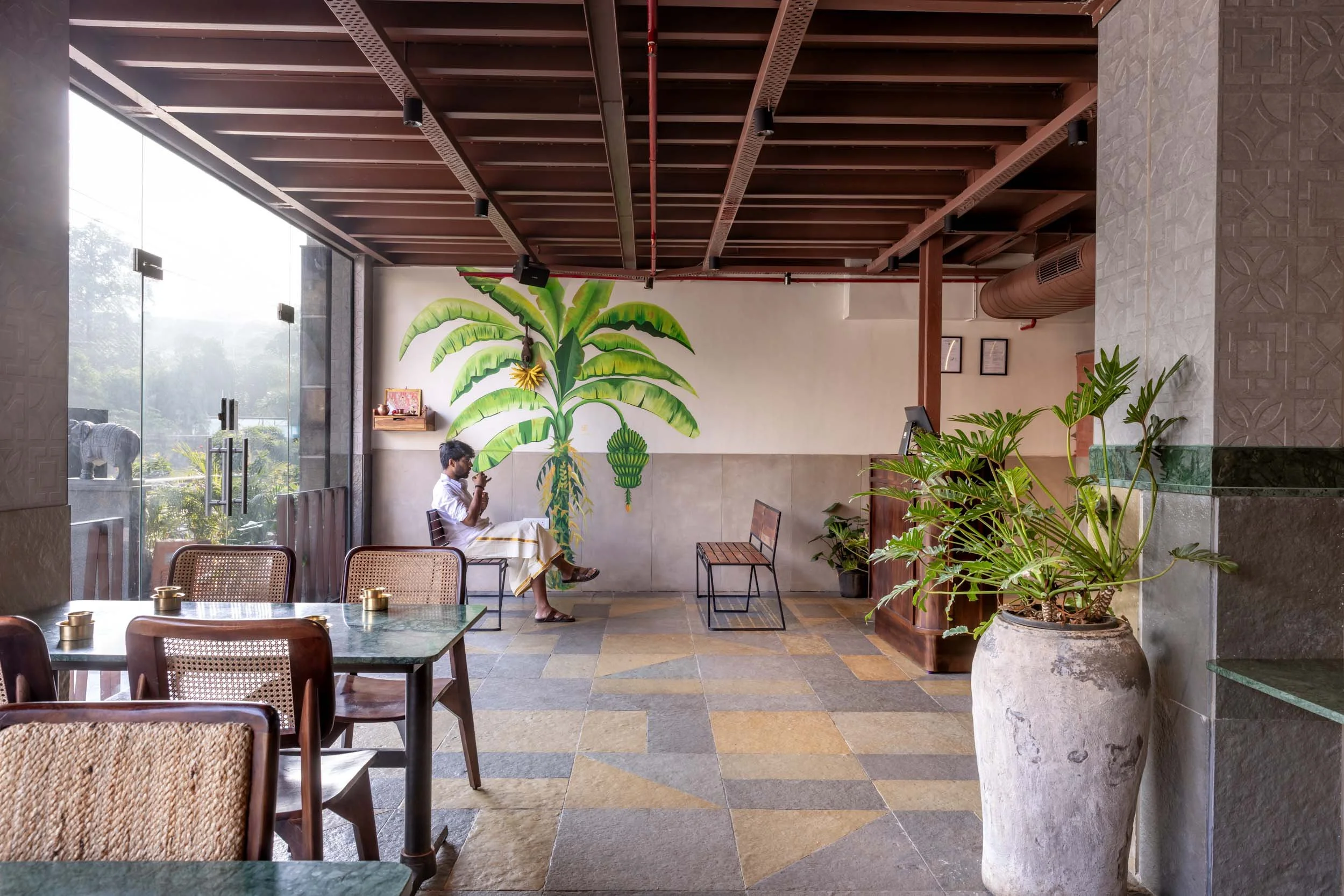 Commercial interior photography showcasing a modern biophilic dining space, highlighting indoor-outdoor restaurant design, natural daylighting, and custom wooden ceiling architecture