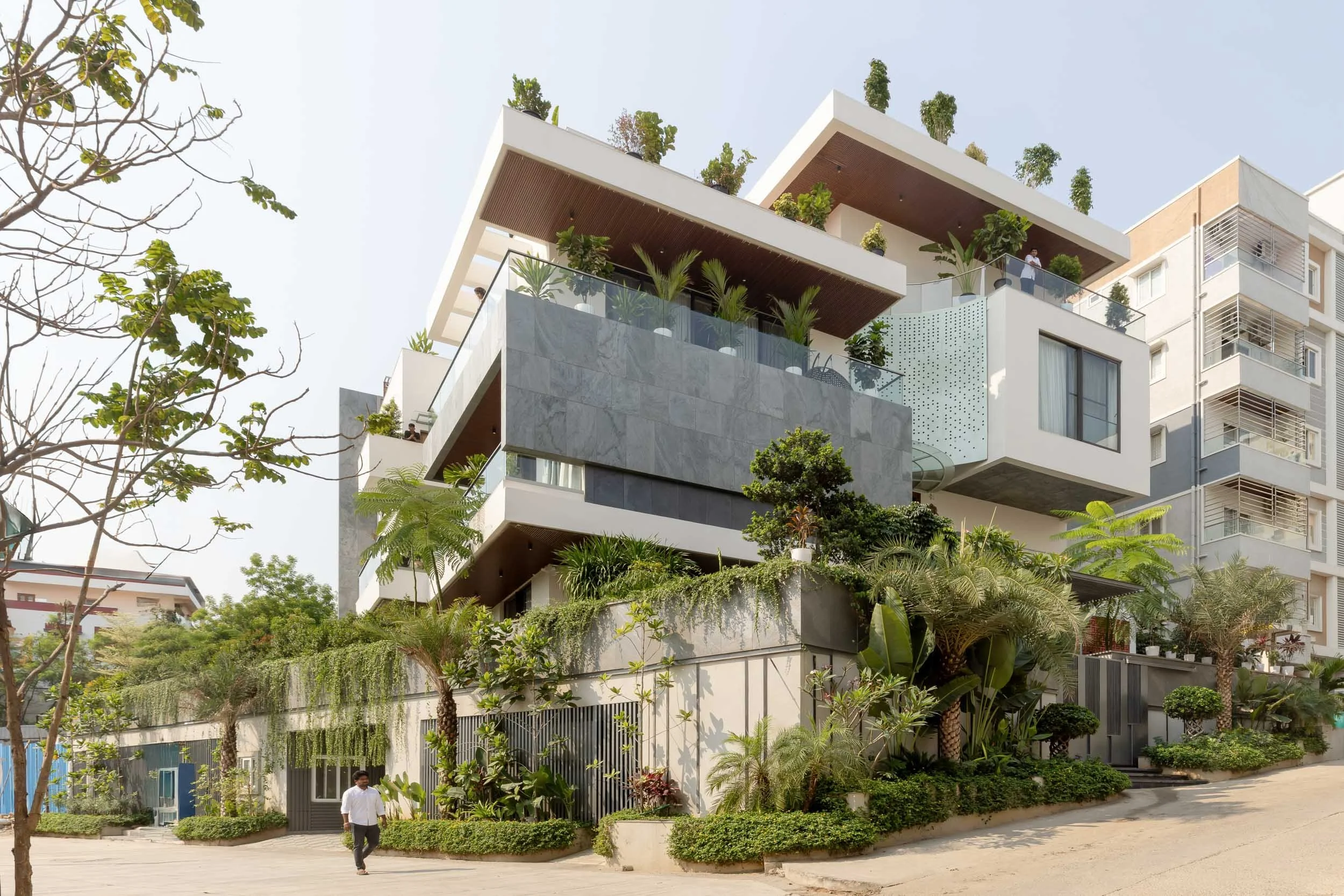 Professional exterior architectural photography of a modern residential home, highlighting a clean white facade, warm wooden accents, and lush garden landscaping.