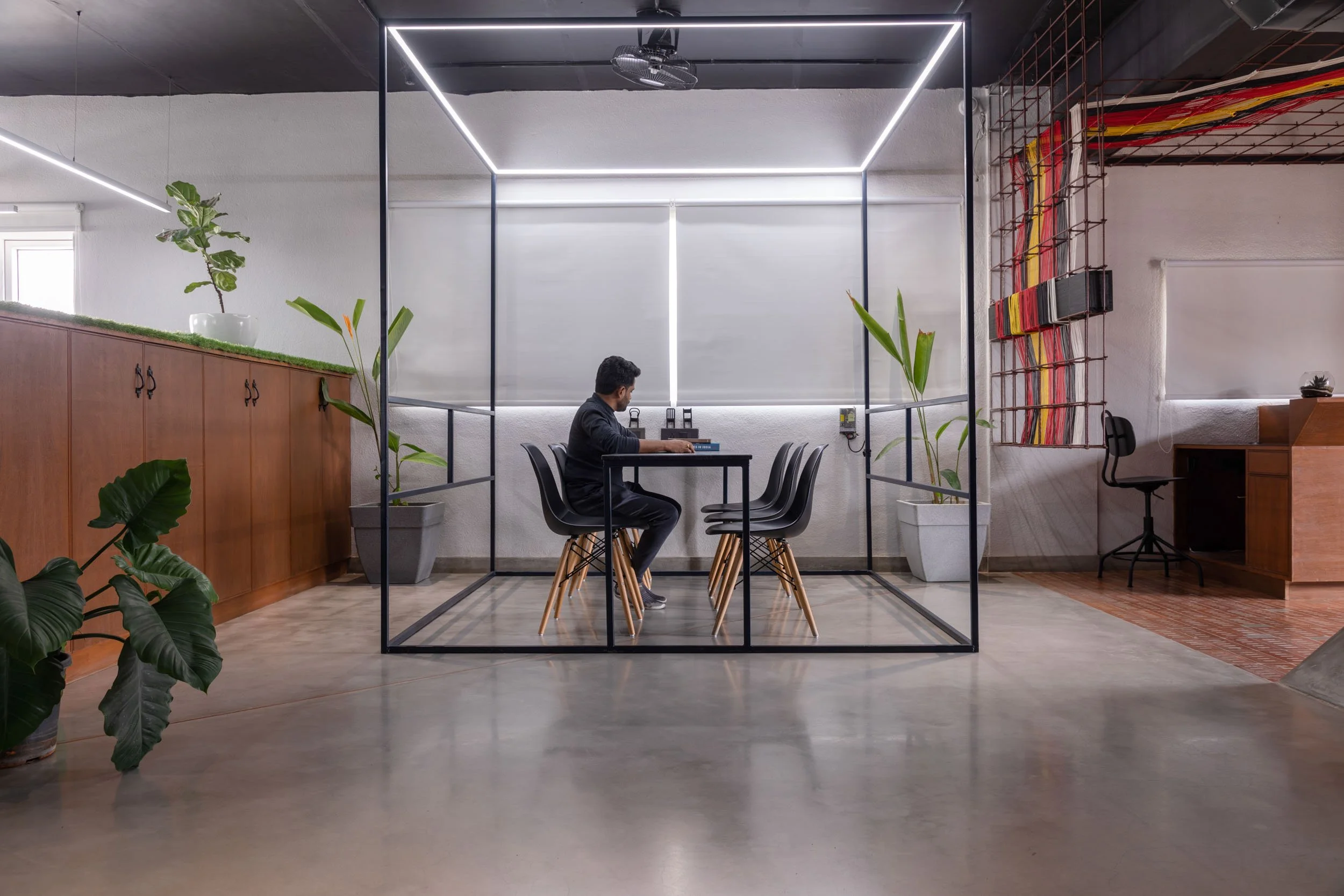 Commercial interior photography showcasing an innovative corporate office design, highlighting a transparent glass meeting pod, industrial ceiling elements, and a collaborative workspace.