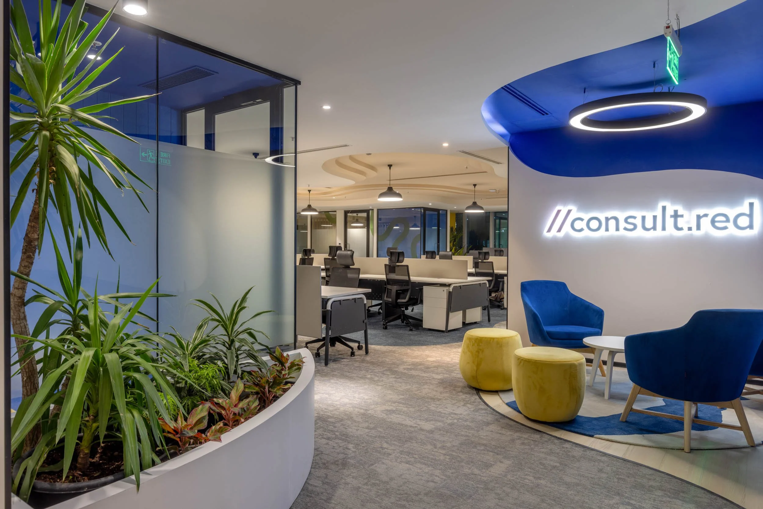 "Commercial interior photography showcasing a modern tech office design, highlighting flexible workspace zones, an industrial exposed ceiling with custom lighting, and colorful ergonomic furniture