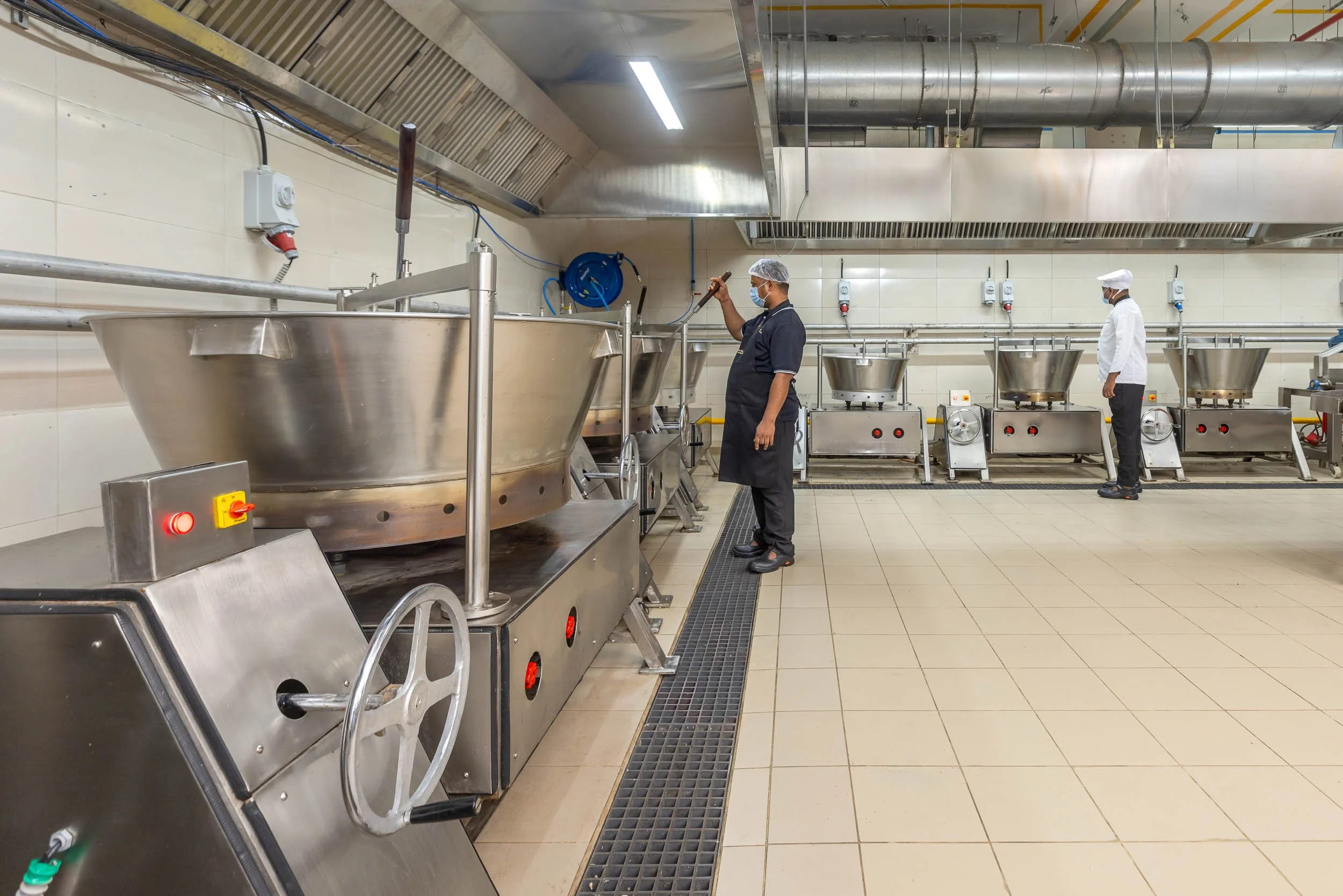 Interior industrial photography of a long, clean production line with stainless steel machinery in a modern food and beverage manufacturing facility