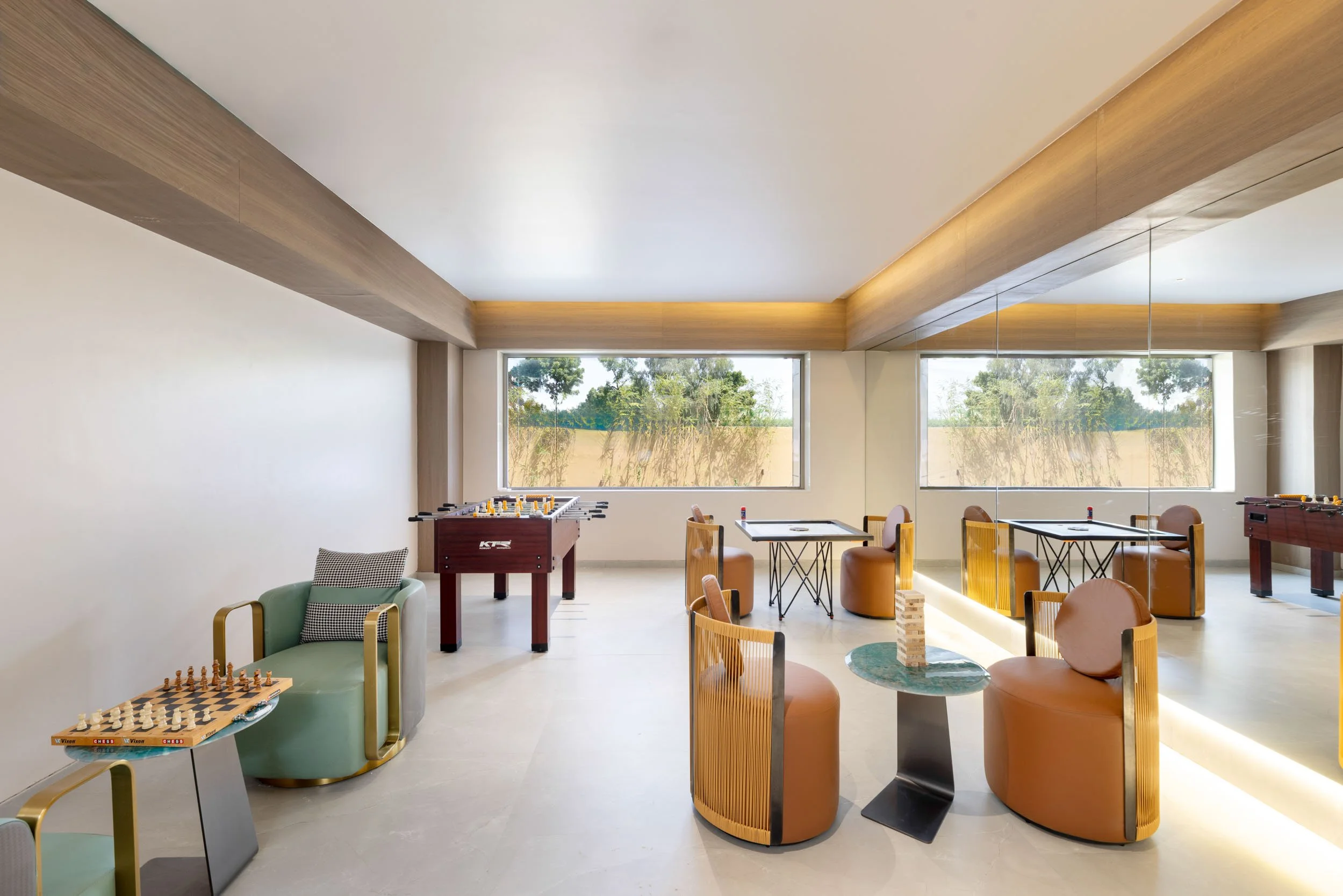 Interior photography of a bright hotel lounge featuring modern seating with green and beige chairs, round tables, large windows, and a tray ceiling.