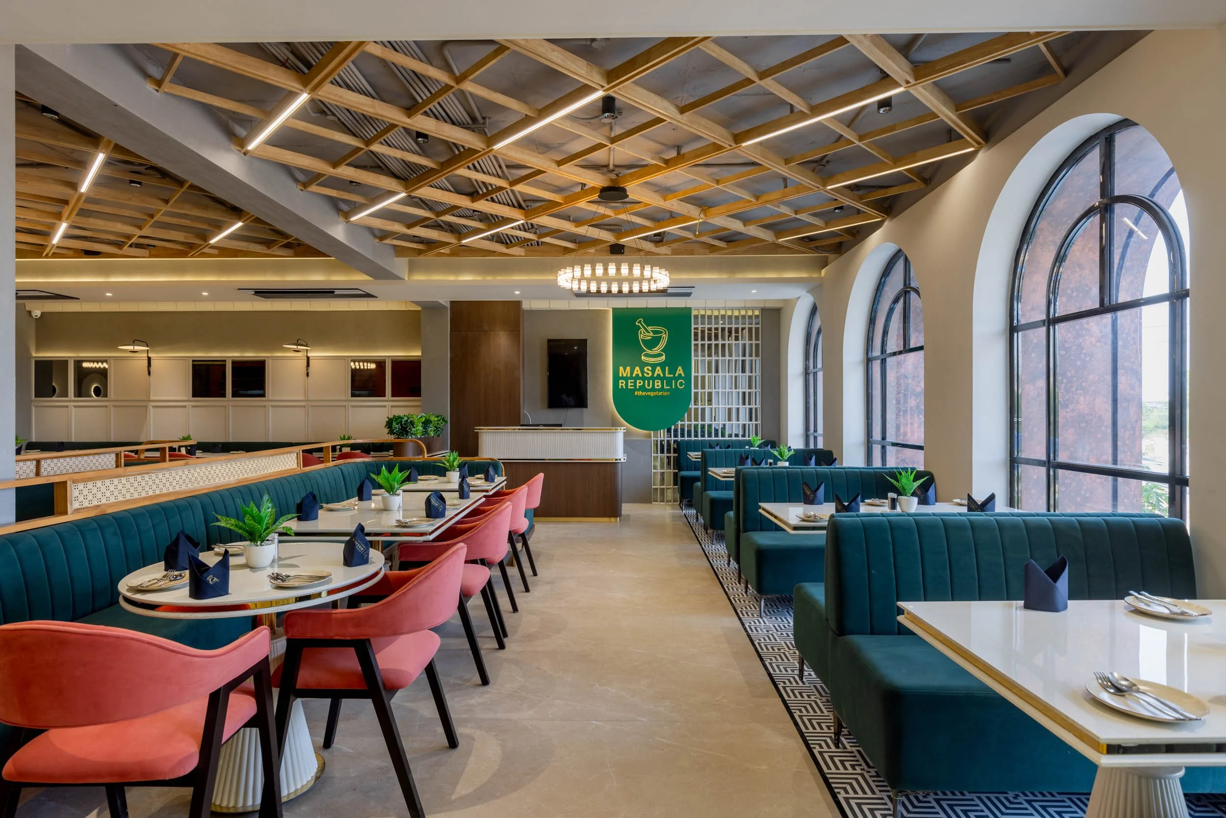 Commercial interior photography showcasing a spacious restaurant dining hall, highlighting custom wood ceiling design, arched windows, natural daylighting, and modern eclectic hospitality seating
