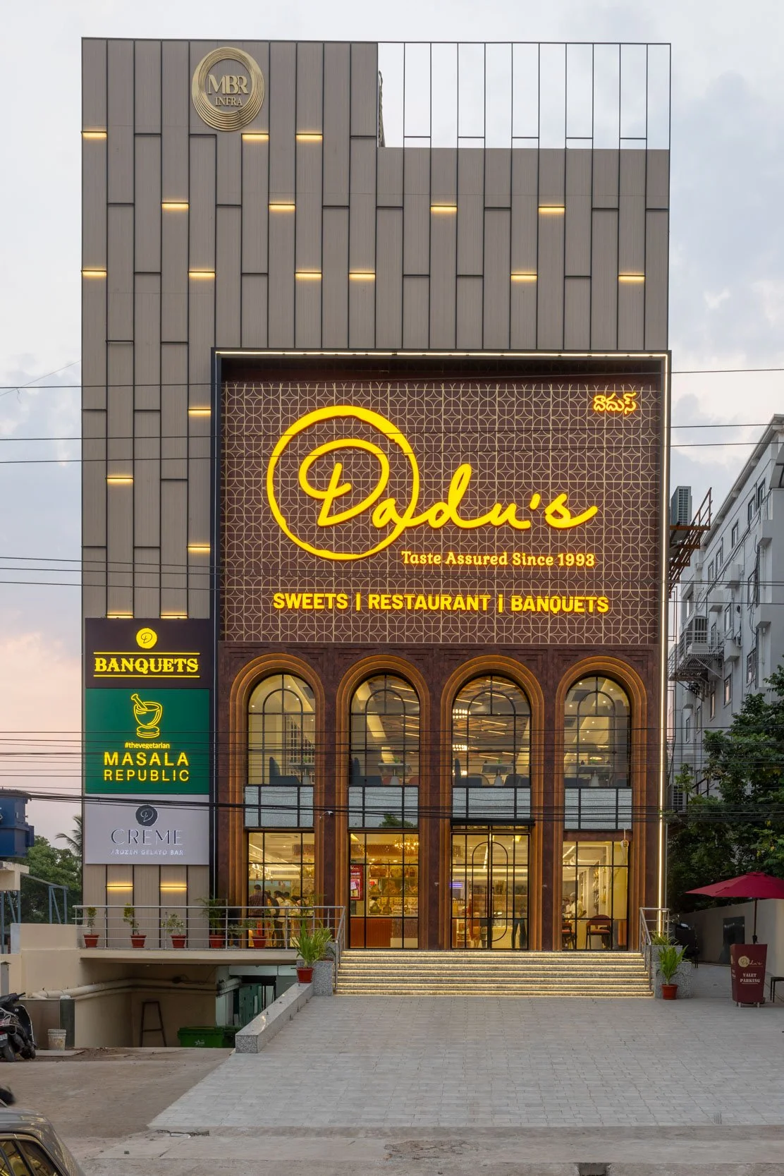Commercial architectural photography showcasing a restaurant or retail storefront exterior at dusk, highlighting custom facade design, large arched windows, and inviting ambient lighting