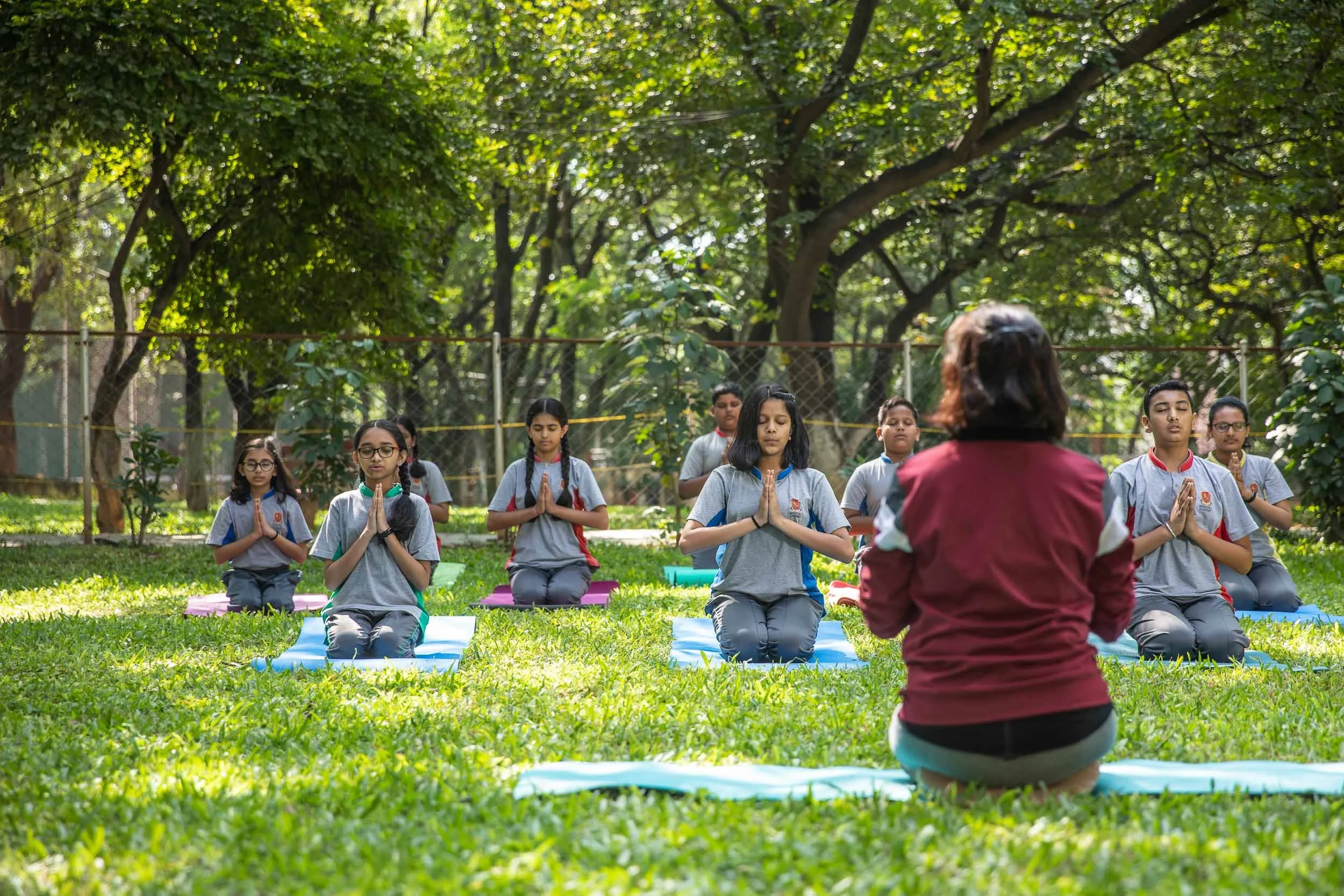 Exterior school photography of students practicing yoga and wellness activities in a lush green campus environment | Ravi Varma Photography & Films