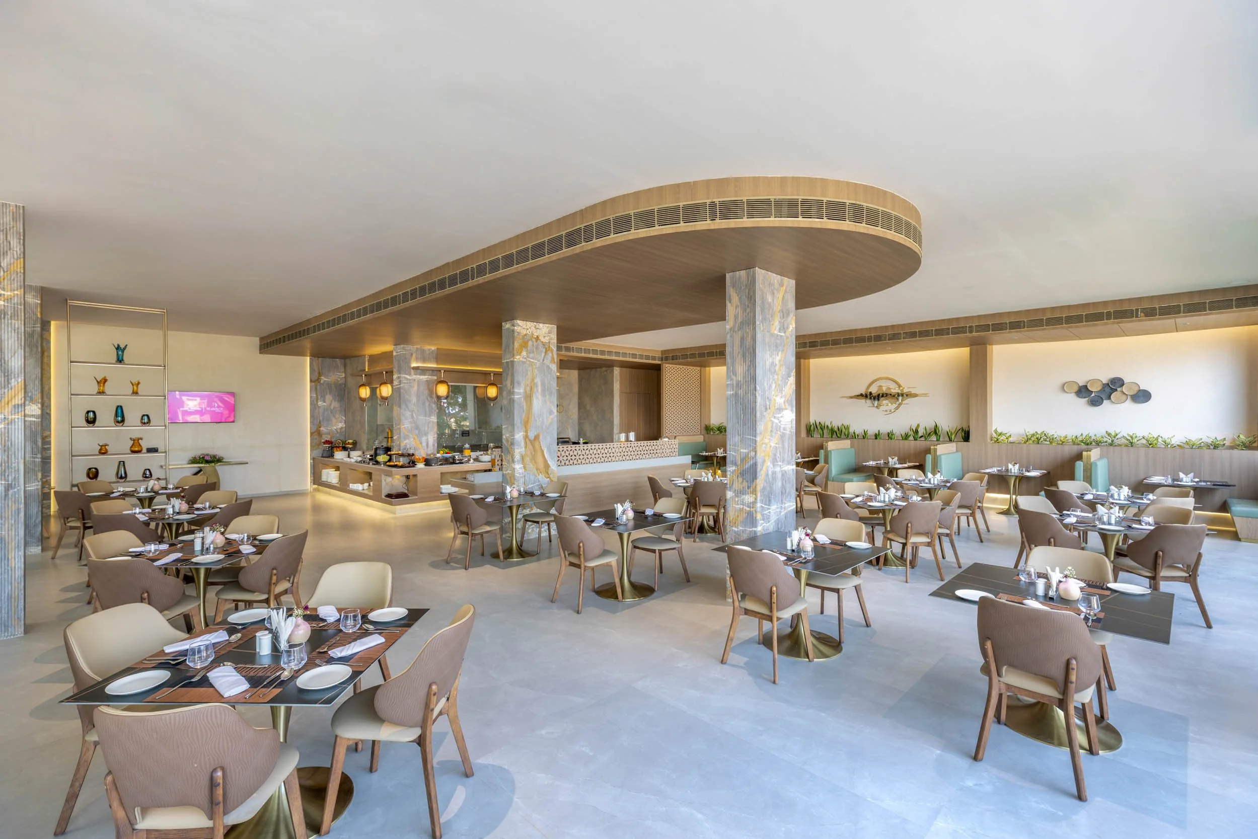 Interior photography of a spacious modern hotel restaurant featuring dining tables, a prominent curved wooden ceiling structure, and bright natural lighting.