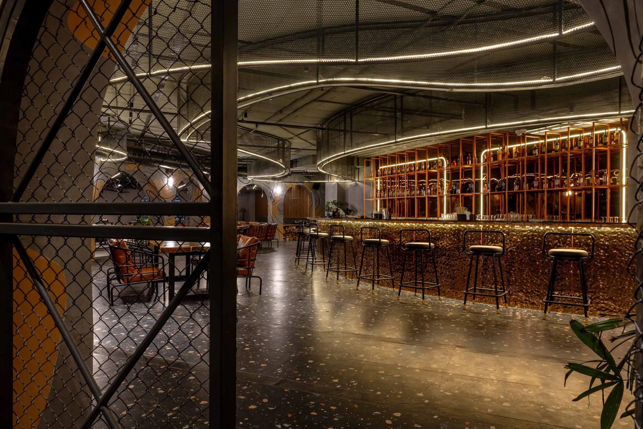 Commercial interior photography showcasing a luxury bar and restaurant, highlighting custom architectural metal partitions, mood lighting, and modern hospitality interior design