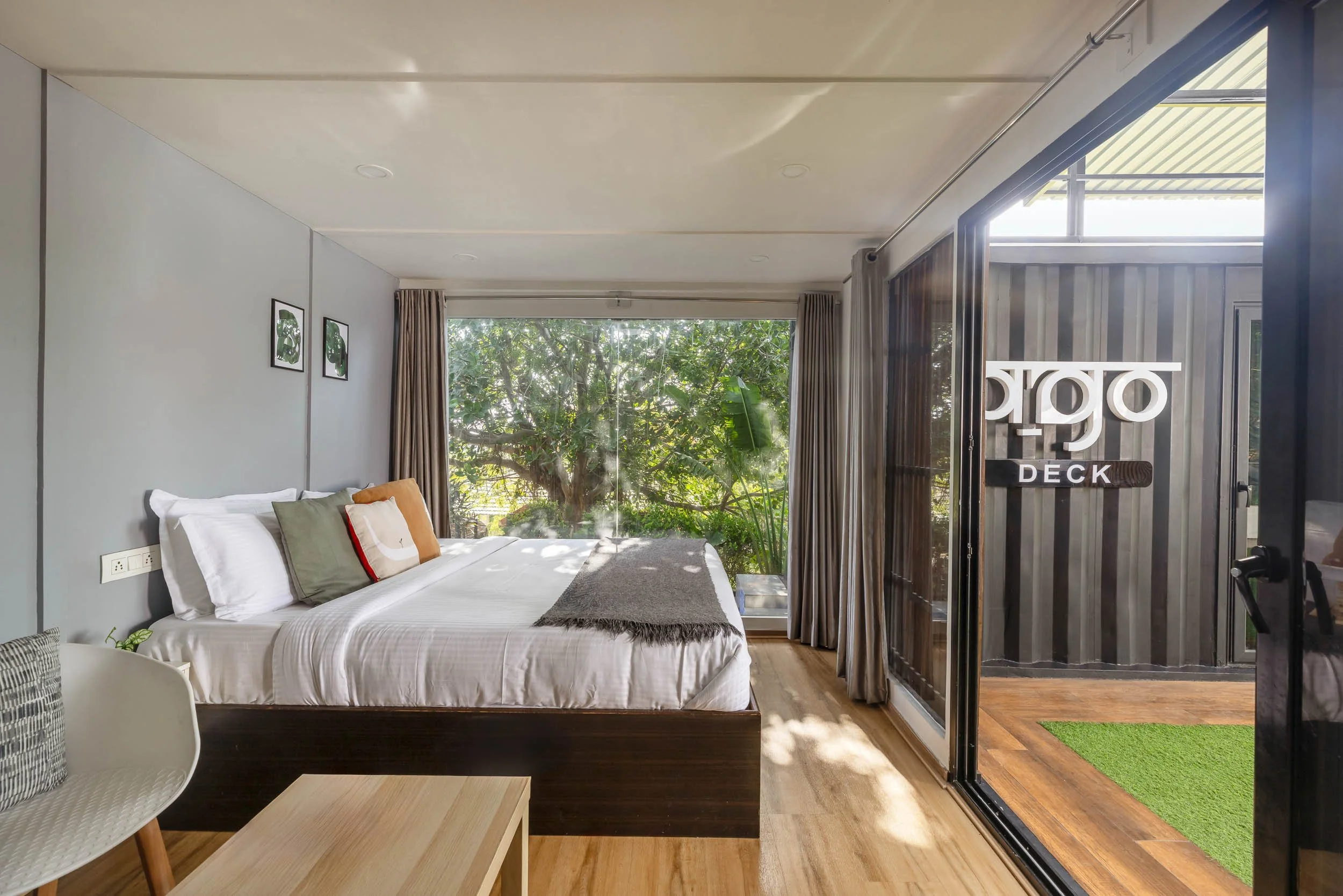 Interior and exterior daytime photography of The Fargo staycation in Hyderabad, showing a bedroom with open sliding glass doors leading to a private covered patio and branded black container wal