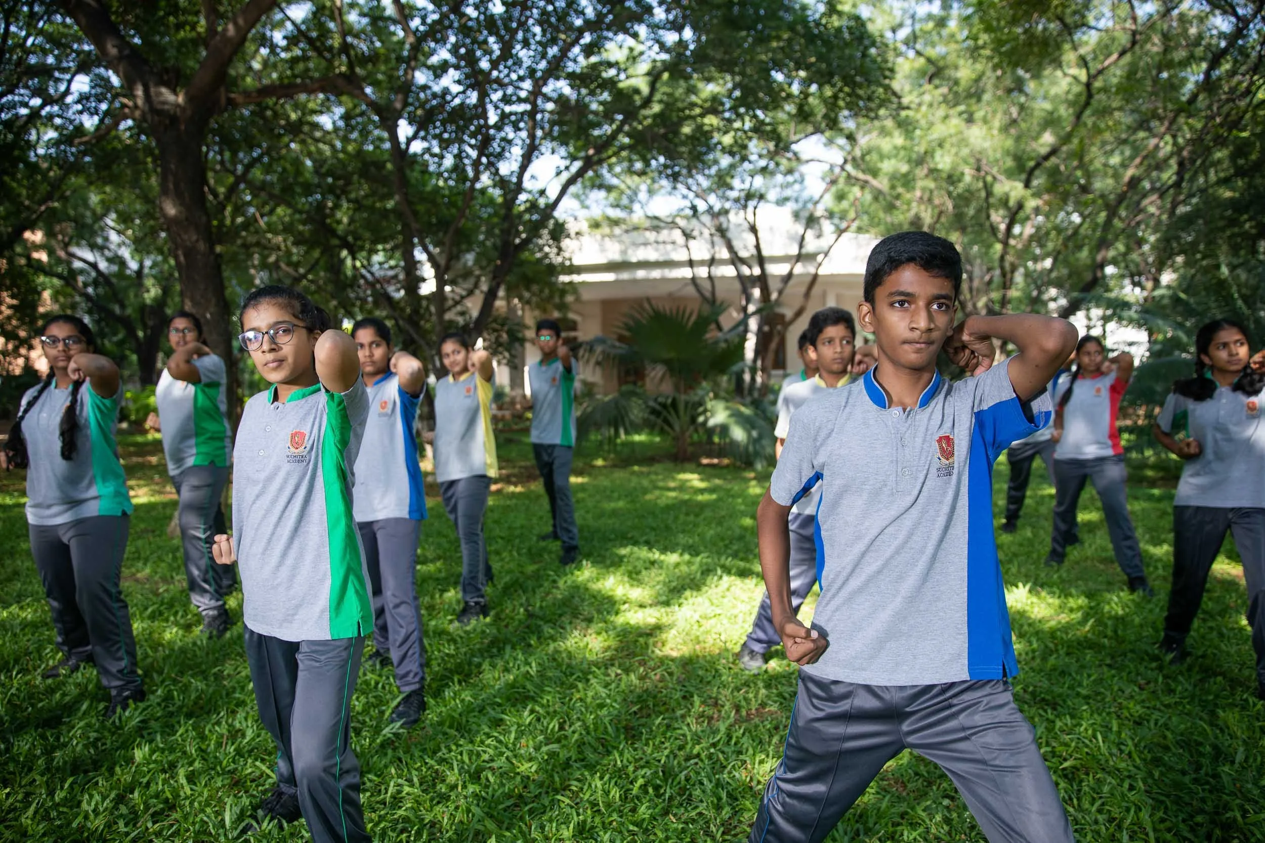 Exterior school photography of students participating in an outdoor activity on a tree-lined campus pathway