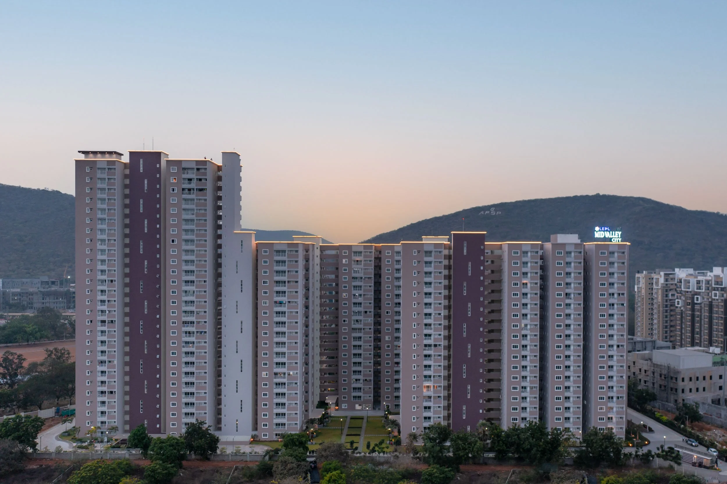 Residential real estate photography capturing a modern apartment complex at dusk, highlighting expansive urban architecture, evening lighting, and mountain views